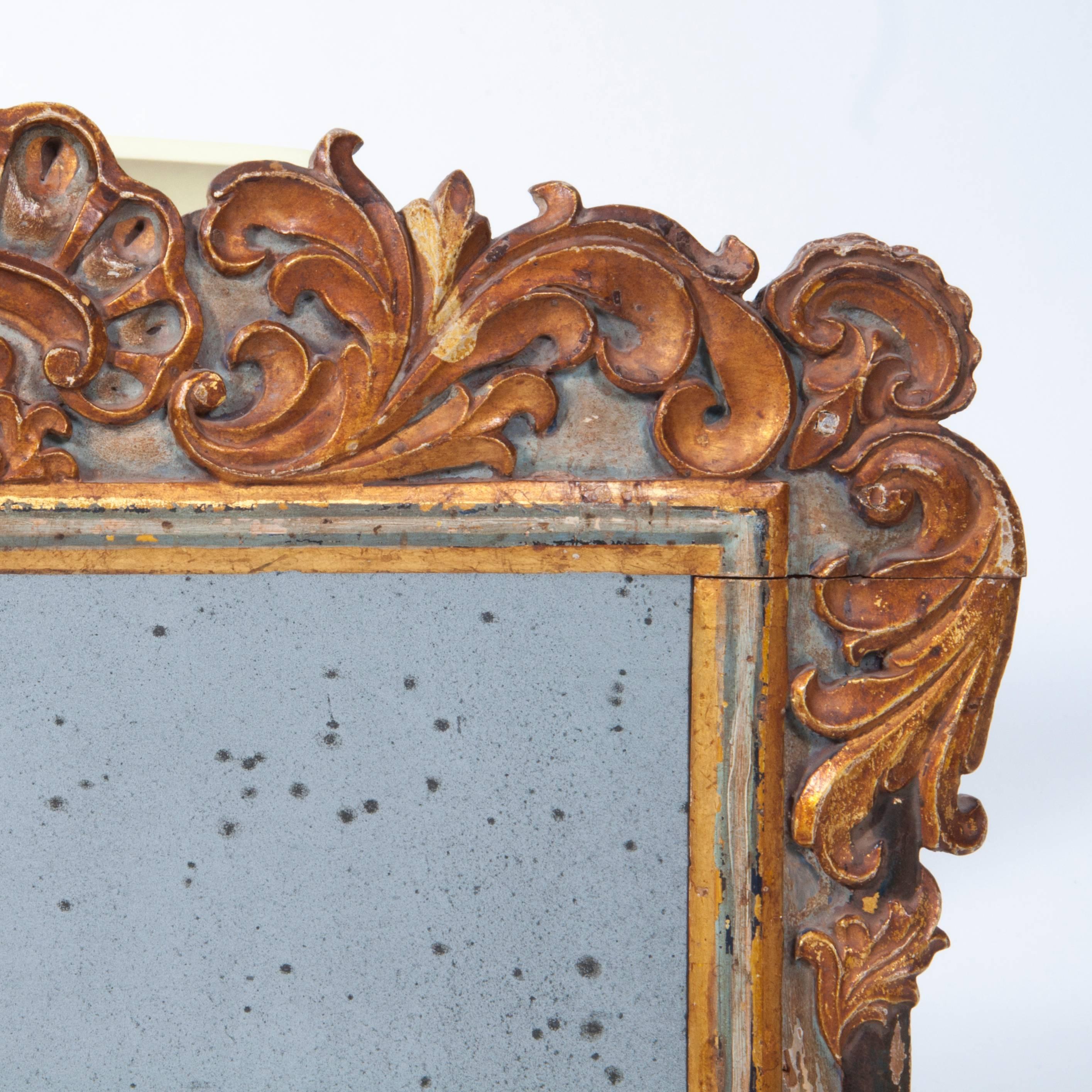 An excellent 18th century gilded wood wall mirror with exceptional foliage carving and a Baroque rocaille crest with original mercury glass and a beautiful patina.