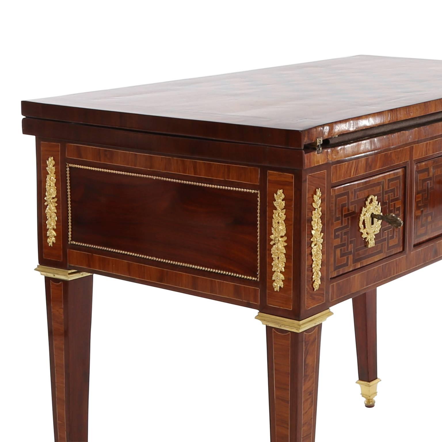 Outstanding transformation table with an integrated chessboard on the top of the plate. Convertible to a card table with square table top covered with cognac-colored leather and gold ornaments. Hinged reading desk. Stamped with N. PETIT as well as
