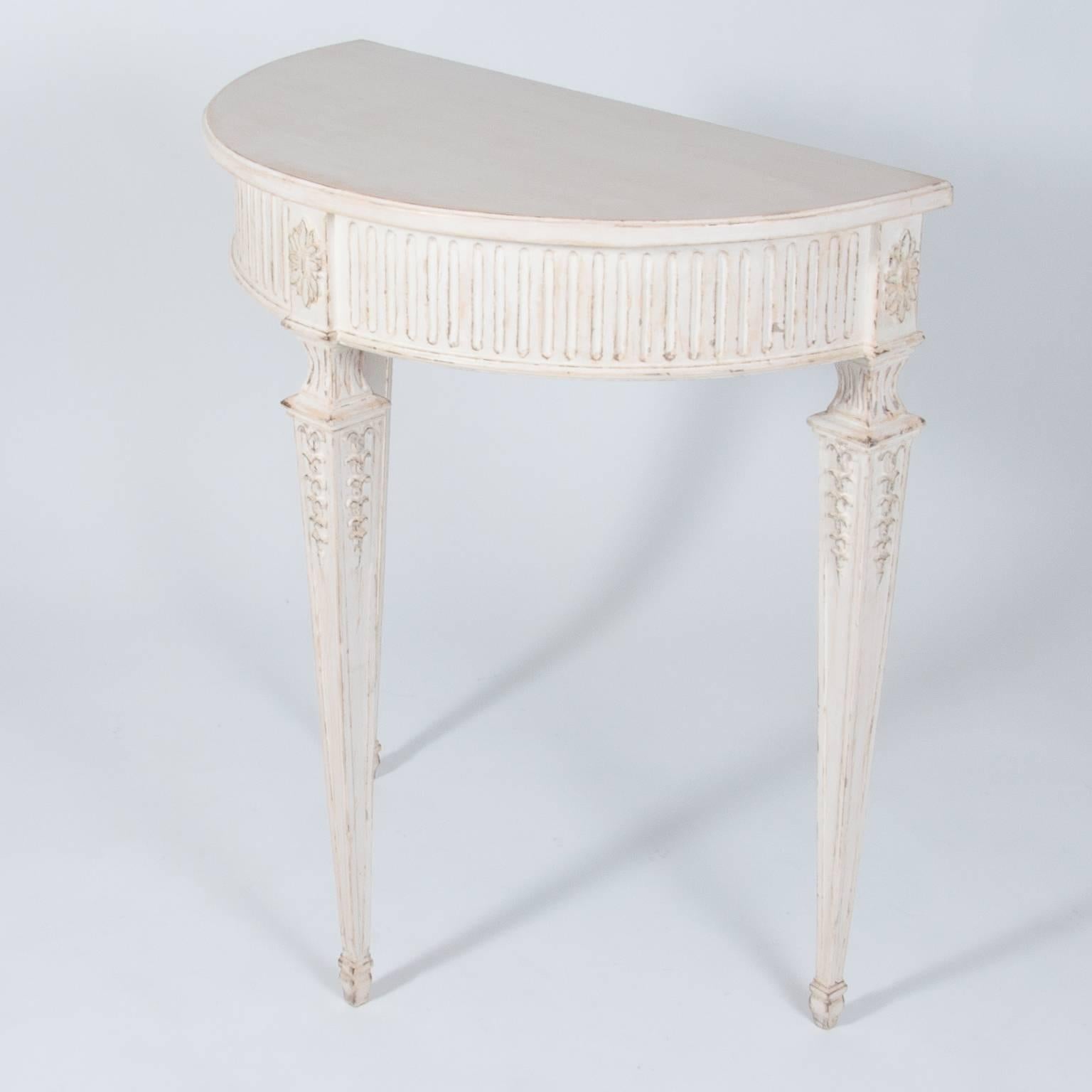 A very nice smallSwedish Gustavian Style demilune console from the 20th century. The table features carved rosettes with lamb's tongue carving on the apron; raised on square, tapered and fluted legs. The aprons are decorated with applied floral
