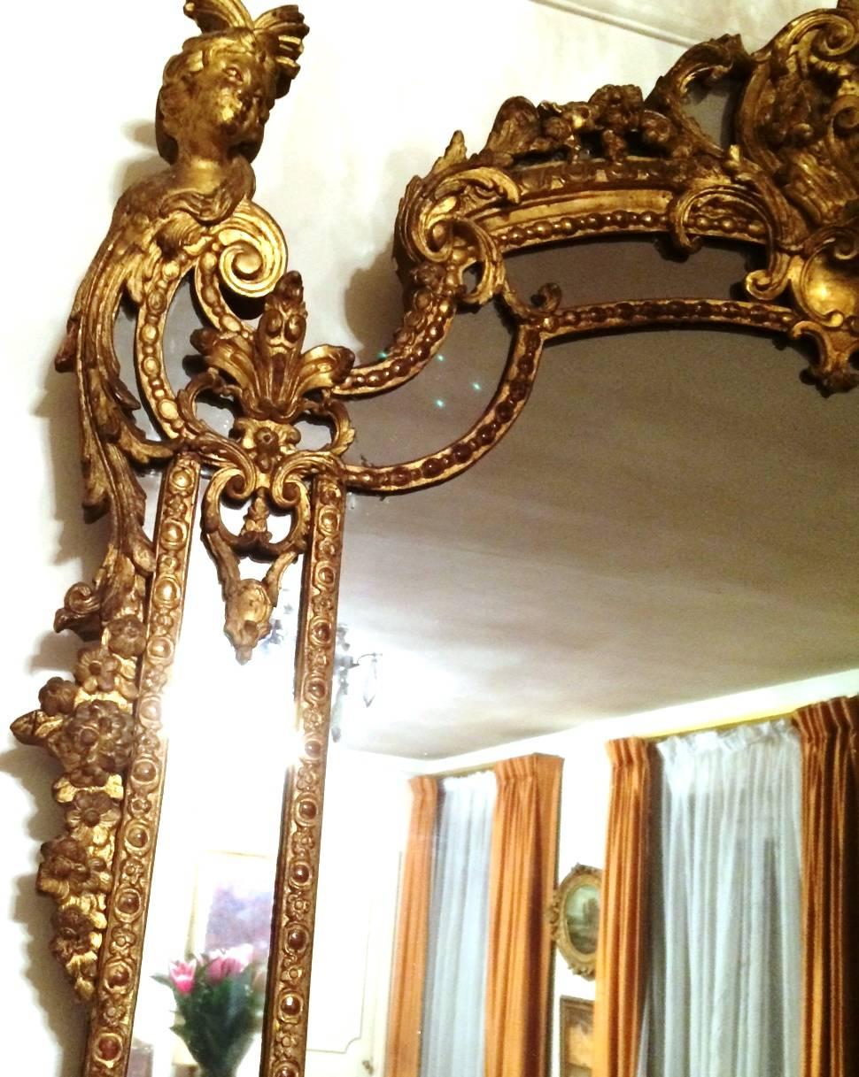 Exceptional French Regence period giltwood boiseries mirror, France, circa 1725 
with various ornaments, such as women's heads, garlands of flowers and fruits, scrolls, etc...

This mirror was exhibited at the Château de Bagatelle in Paris, during