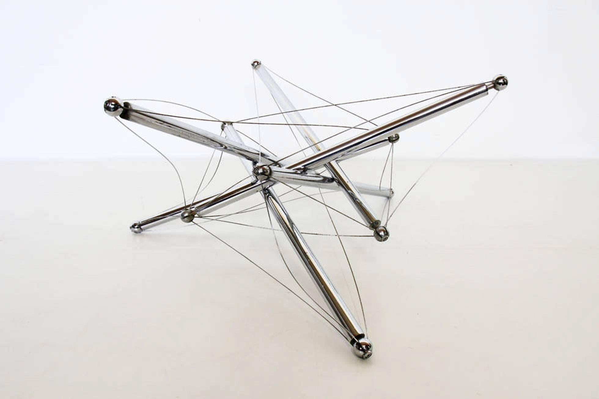Coffee table 713 by Theodore Waddell for Cassina, 1973.
Polished chromium plated steel rods and steel tension wires. 
Glass tabletop with beveled edge under the top.
Some stains on the chromium rods.
 
