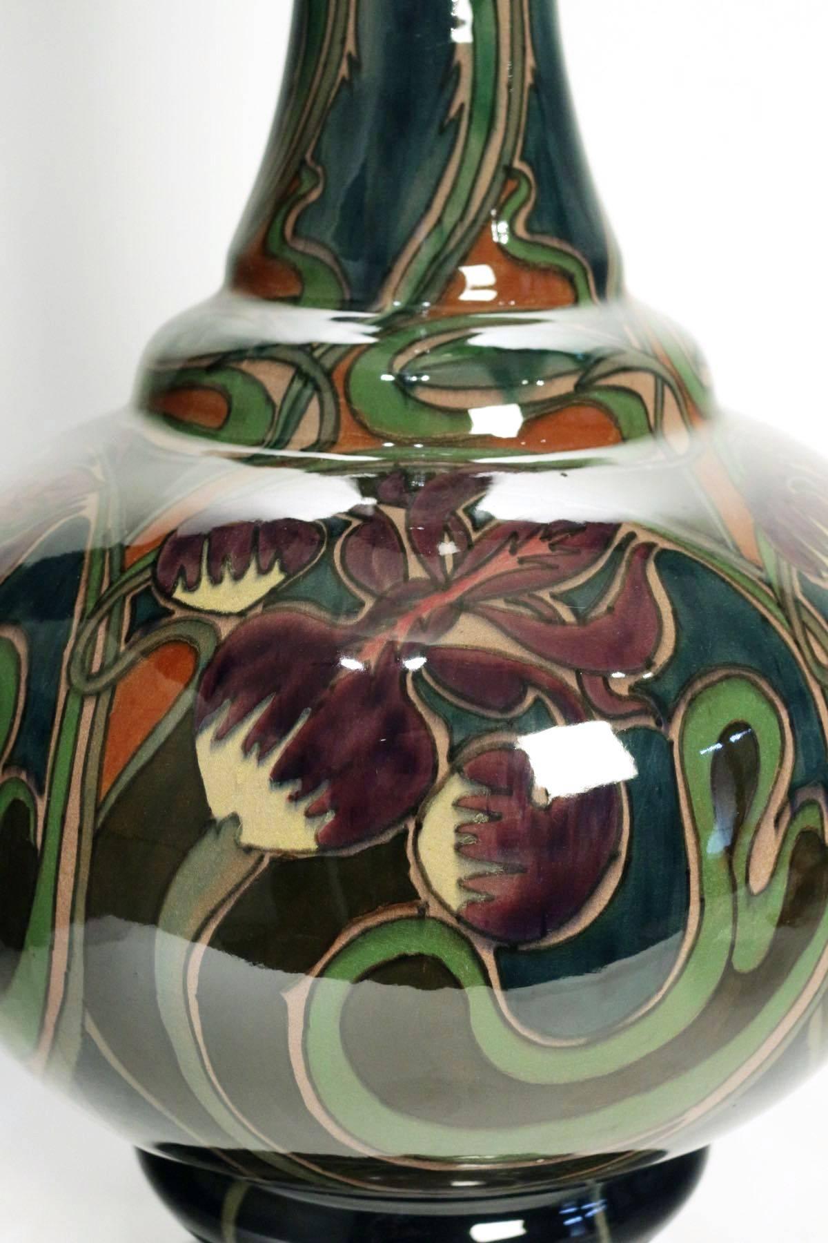 A large Art Nouveau vase by the factory Plateelbakkerij Zuid Holland. Tulips and iris design, signed and monogramed D d j for Daniel Adrianus De Jong,
circa 1900.