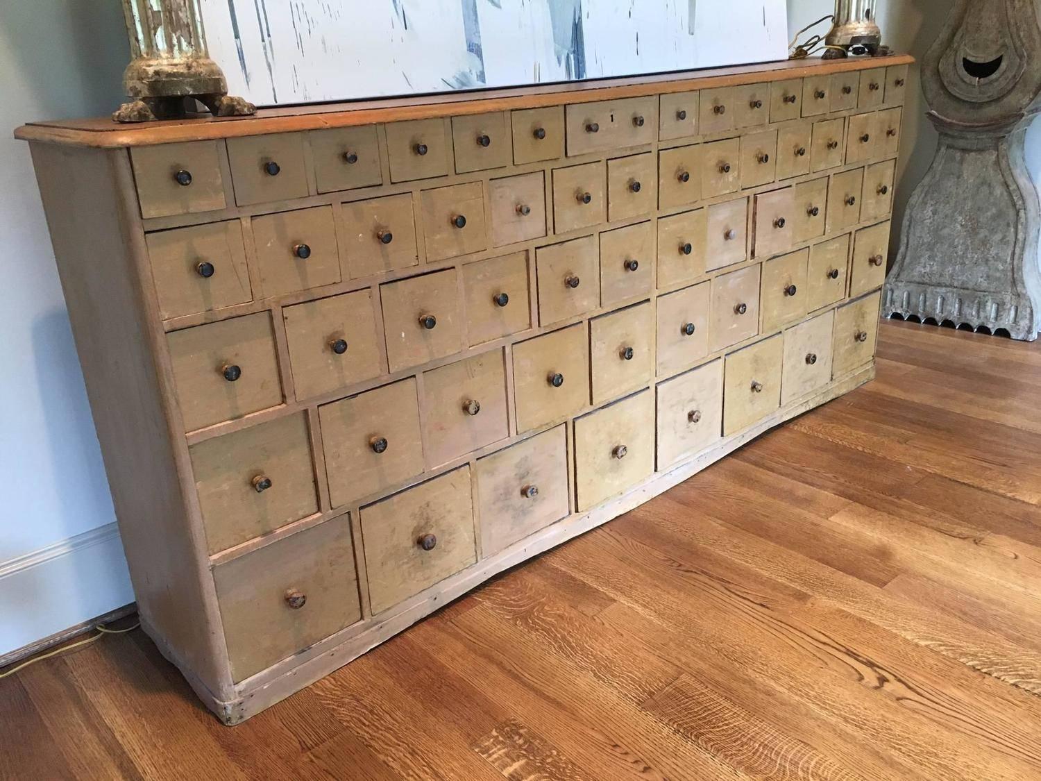 A handsome and well proportioned Swedish apothecary bank of drawers. 16 smaller upper drawers descending five levels to end in eight larger drawers at bottom. In an original pale ochre paint. The bottom skit being cut in two elongated 