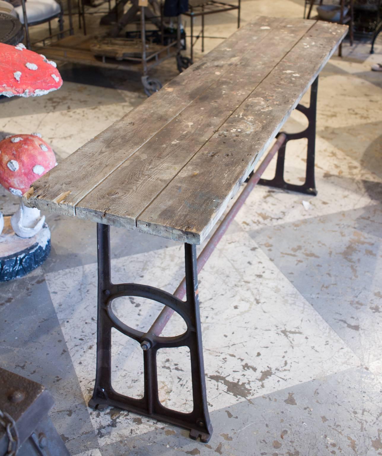 This is a rustic console table we found on our most recent buying trip to France. The top is wood and the base is iron. The base has some reddish toned paint along with an aged patina. The Industrial look of this piece lends itself well for use as a