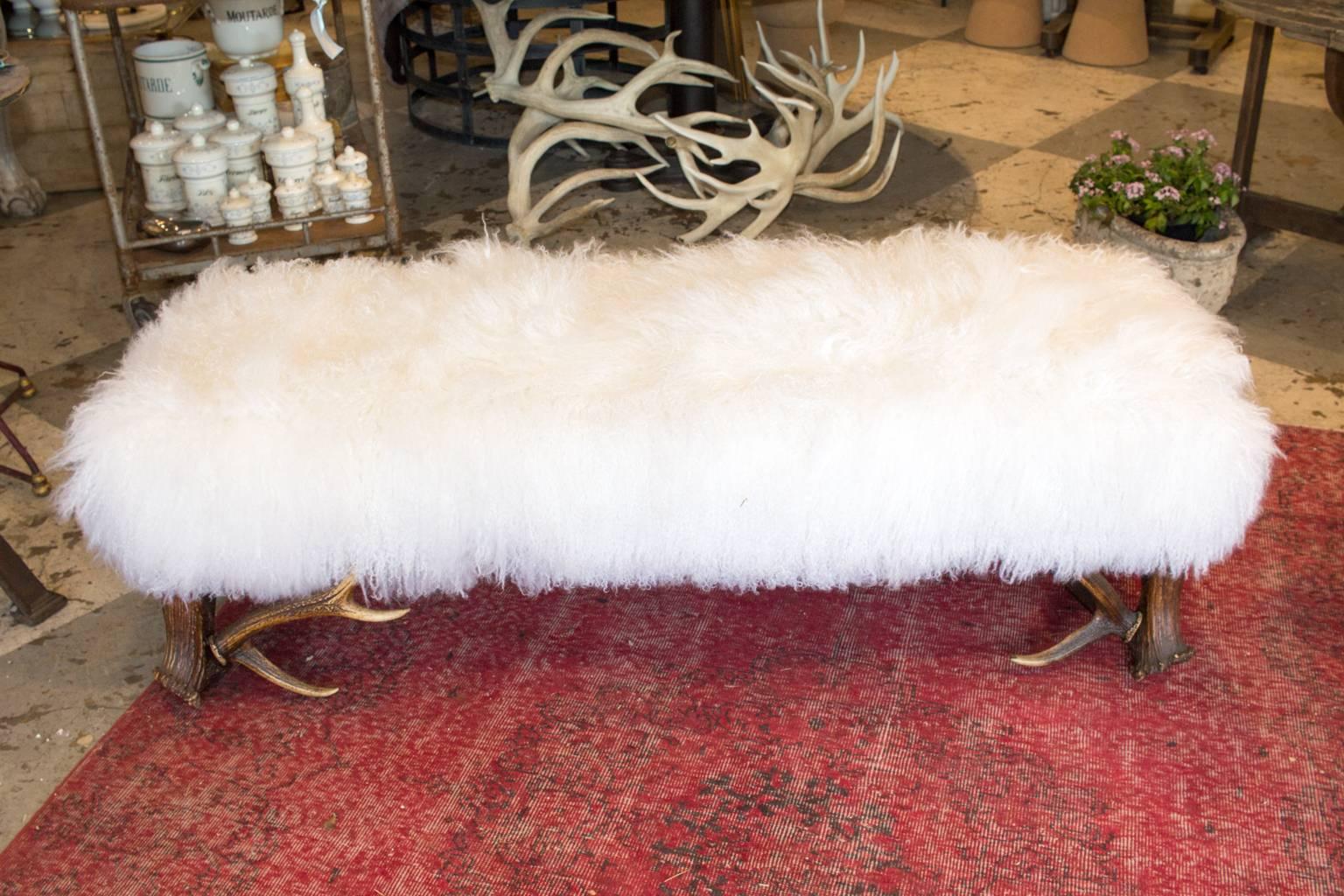 Perfect for in front of a bed or in a library or in your great room near the fireplace. Many options with this versatile piece. Crafted with antique Habsburg red stag antlers as the base with a white Tibetan lamb fur seat. High-density foam seat