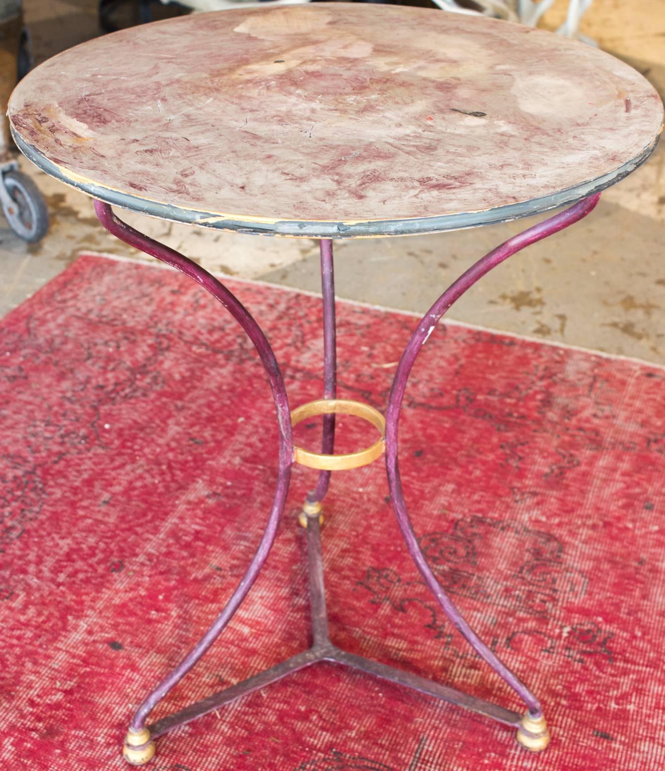 This charming bistro table was found in Northern France. It is metal, but has been painted in a warm purple with gold accents. This table can be used indoors or out and the distressed finish only adds to its charm. Measures 29