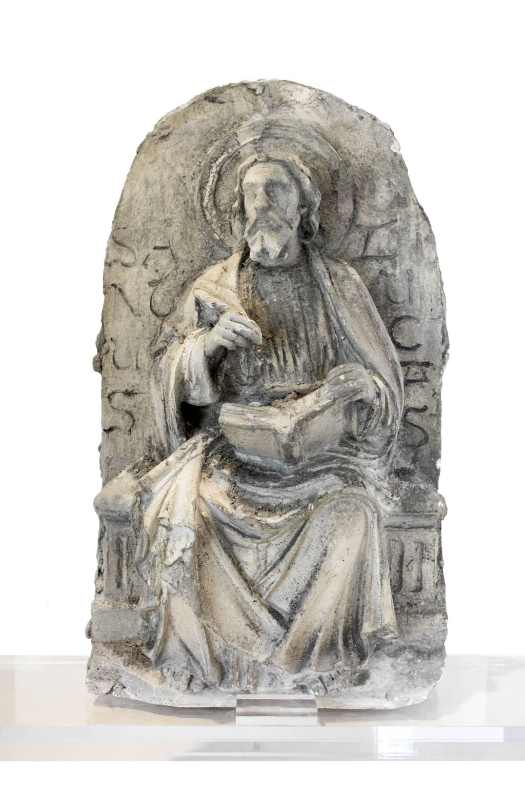 Truly a very special one of a kind piece, this plaster religious altar fragment features the lovely iconic image of the seated St. Luke the Evangelist and includes an acrylic base. Recently discovered in Bruges, Belgium and is the considered the