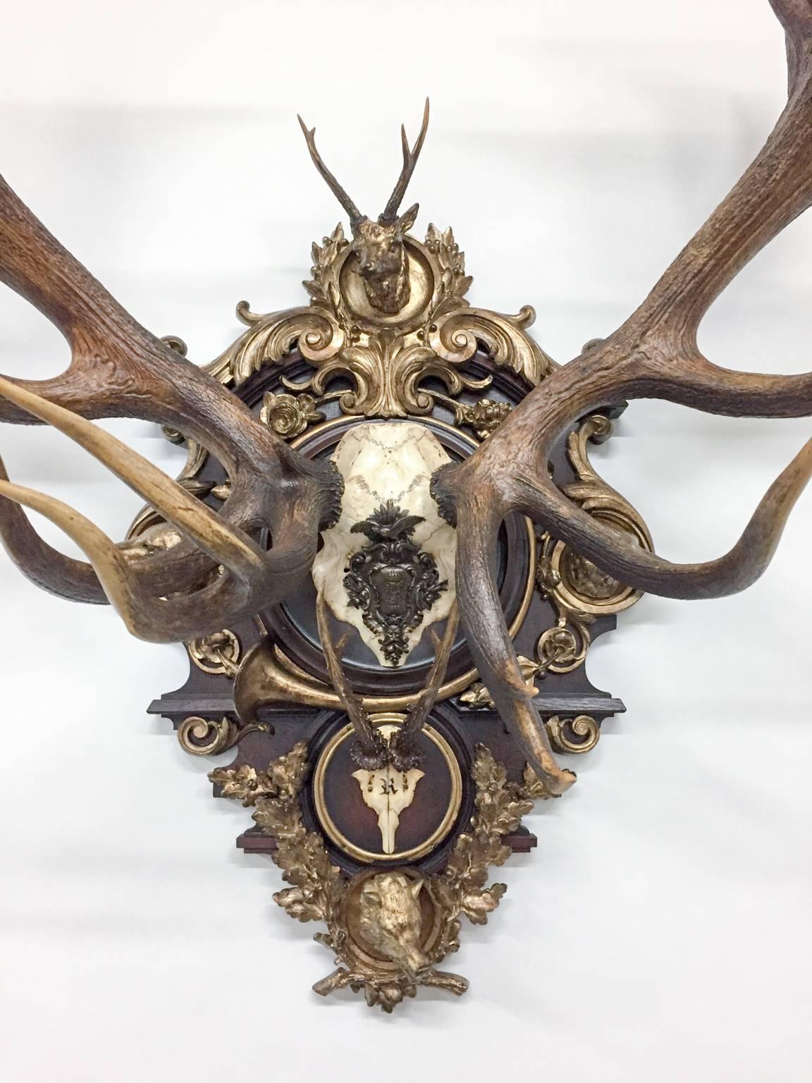 This extraordinary Red Stag is quite large making it a tremendous statement piece measuring 59 inches tall, 52 inches wide and 31 inches depth. Featured on the gilt plaque are four animals that surround the red stag all in gilt bronze: the Fox,