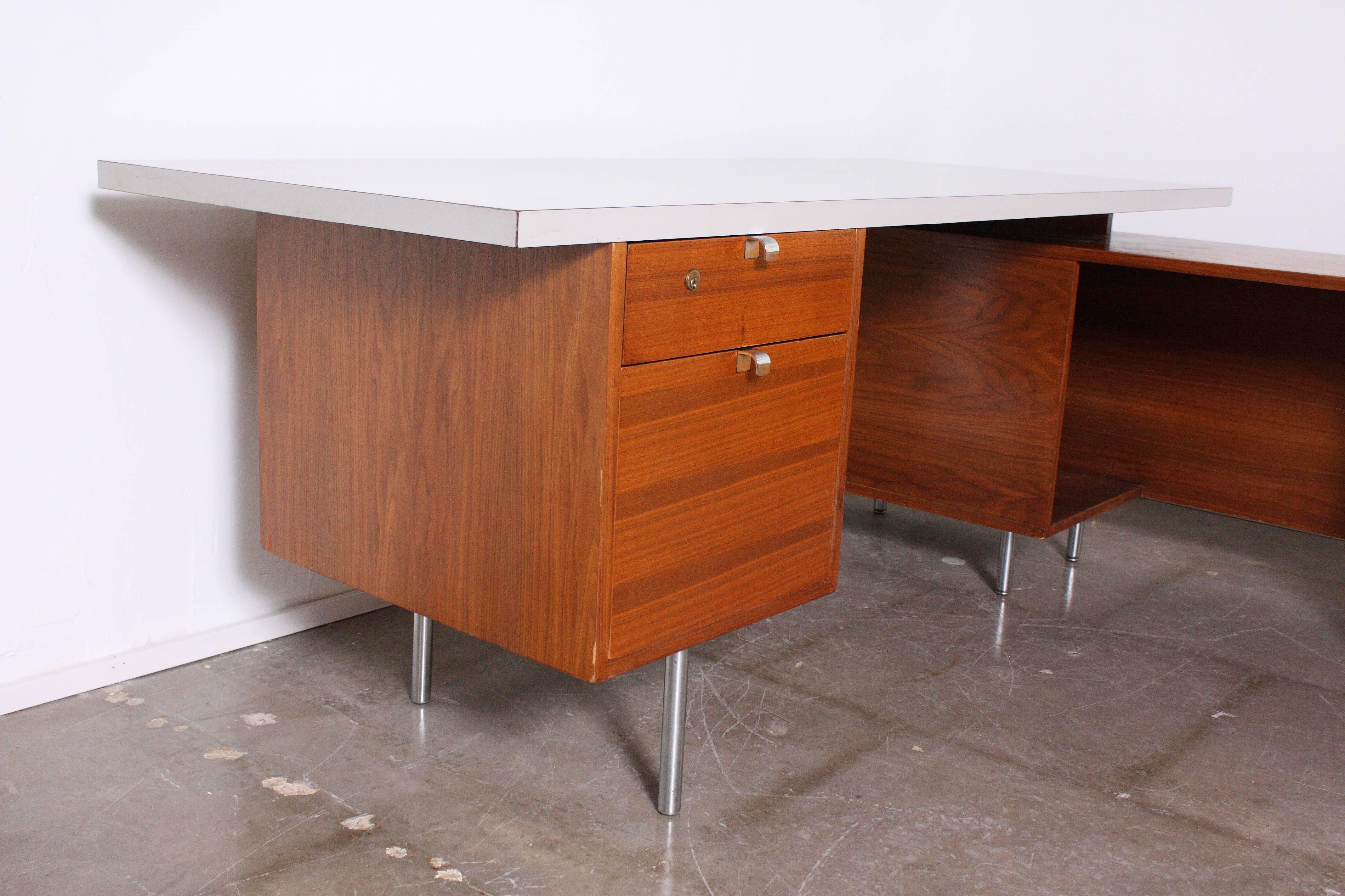 Executive desk by George Nelson for Herman Miller with return and light grey formica style top. Desk sits on steel tubular legs. Six drawers and cabinet with shelf for storage. 

Desk top measures 72