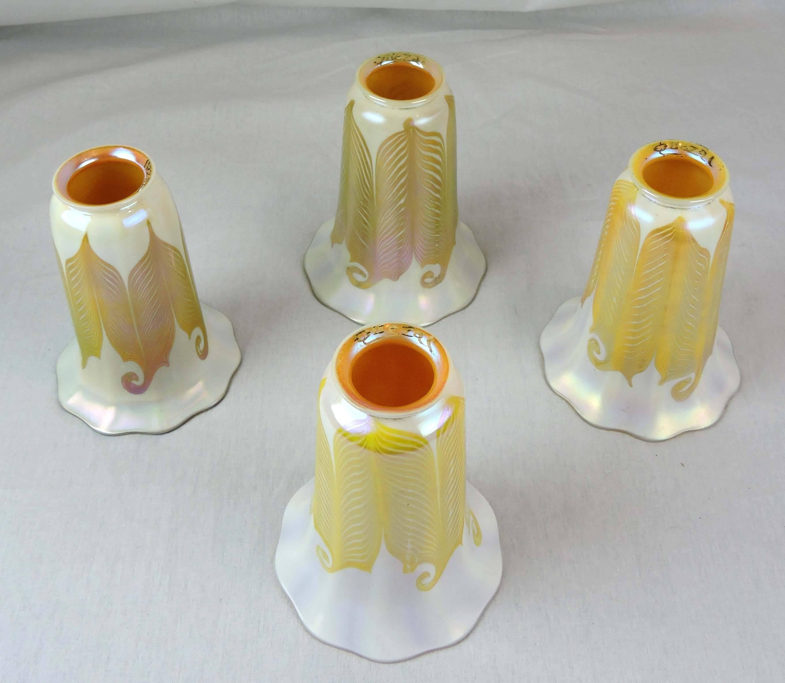 This is a set of four, matching American Art Nouveau art glass shades by The Quezal Art Glass and Decorating Co, which operated in New York City between 1902-1925.

The exterior of each flower-shaped, fluted, columnar shade is decorated with a
