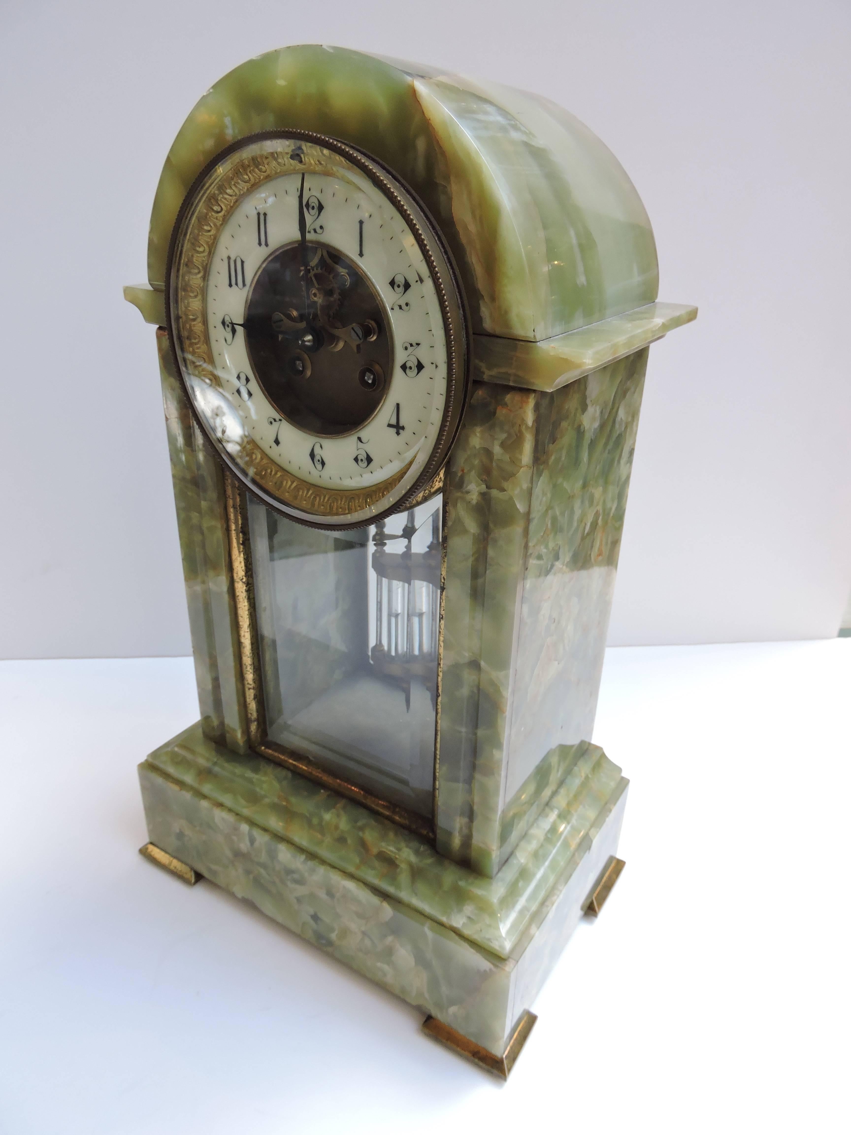 A lovely shaped French clock in a translucent green onyx stone. Glass front and back which displays the mercury pendulum. Chimes on the hour and half hour. 

The face has a glass covering and also shows the a partial skeleton movement in the
