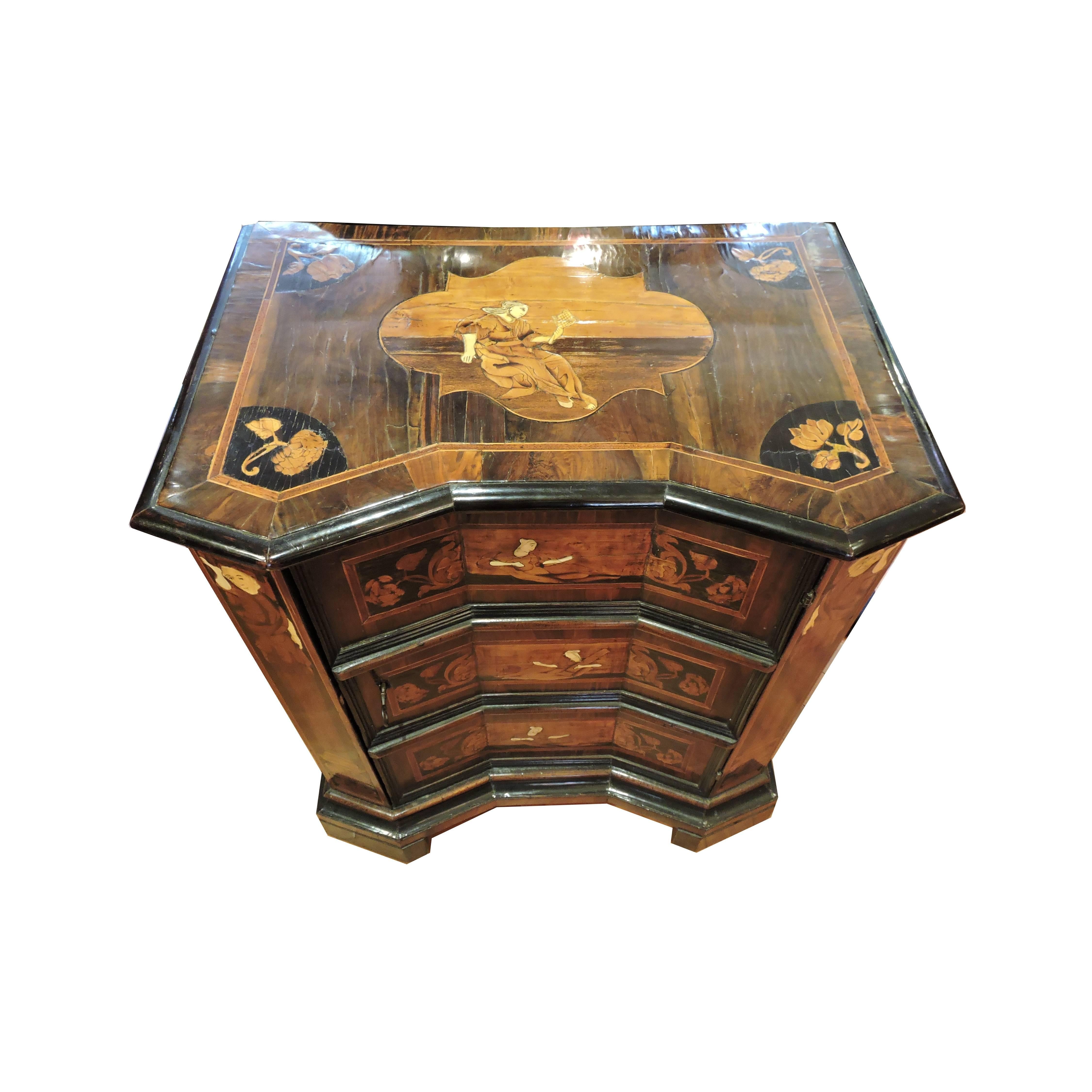 An Italian beautifully inlaid mid-18th century commode / cabinet having one door opening that is in the shape of a three-drawer commode. The walnut has wonderful grain and is bordered by black ebony. The piece is also inlaid throughout with fruit