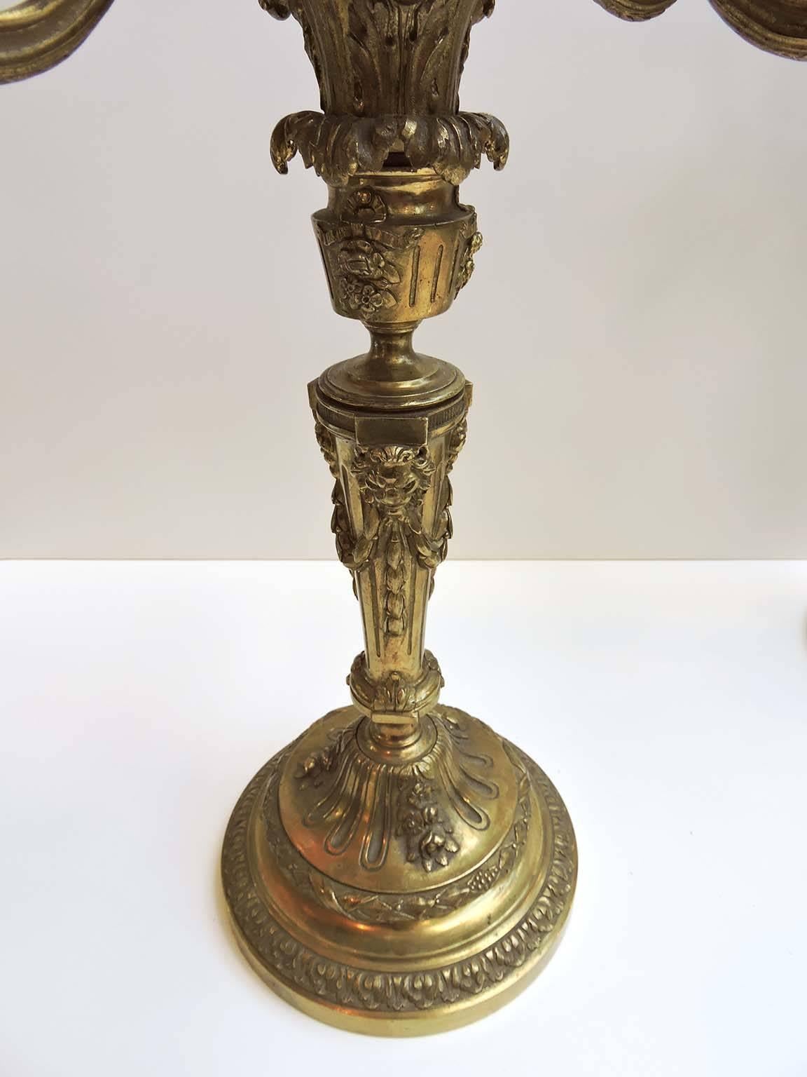 These exceptionally grand gilt bronze candelabras have six scrollwork arms surrounding a raised centre candleholder.

Each of the fluted columnar candleholders has a bobeche with bead banding and a larger drip pan with ribbon decoration.

The