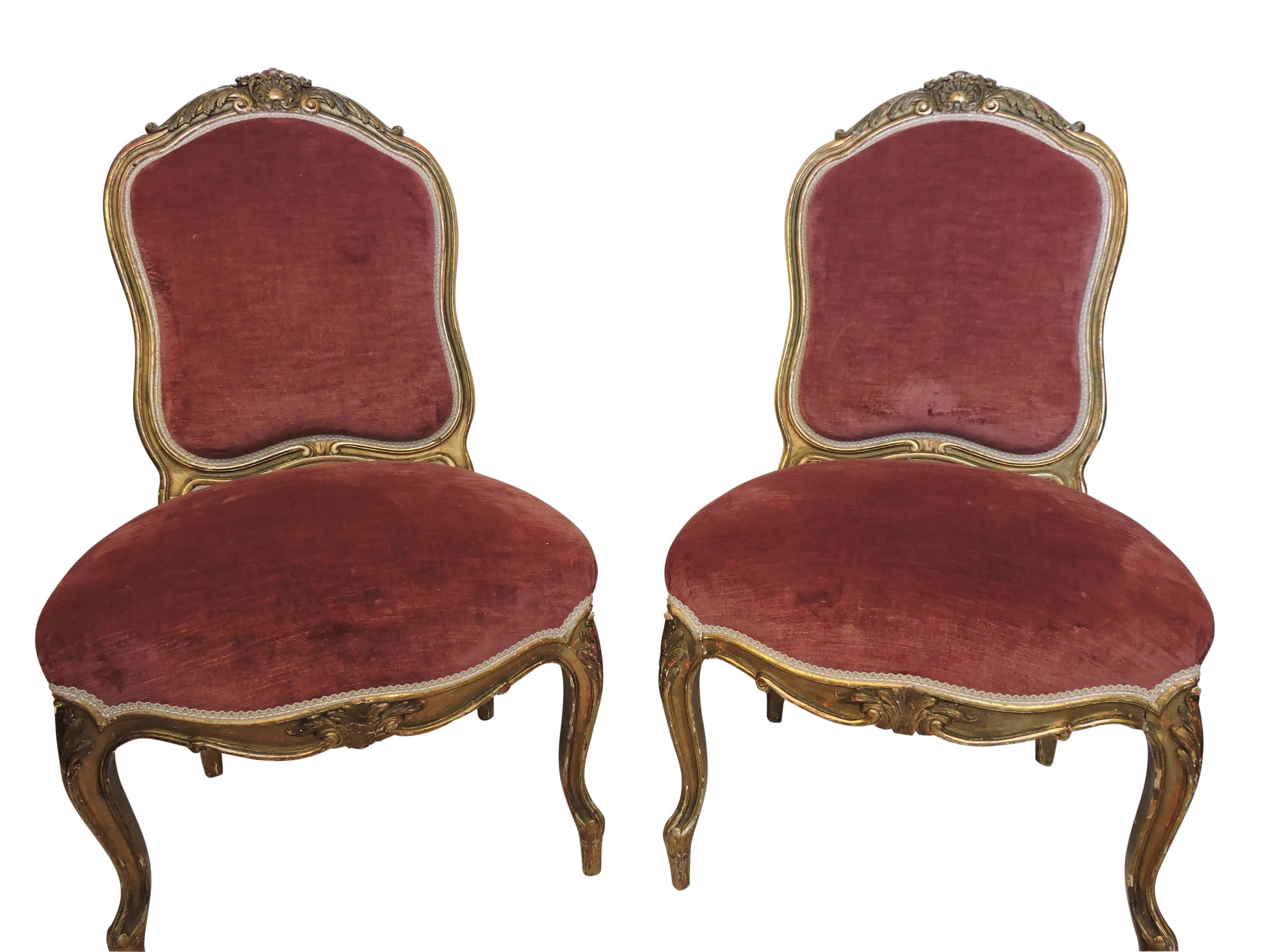 A pair of comfortable and beautiful 19th century Louis XV style slipper chairs, with carved and gilded hardwood frames, cabriole legs and newer rose velvet upholstery, front and back.
The hardwood frames are gilded inside and out and are further