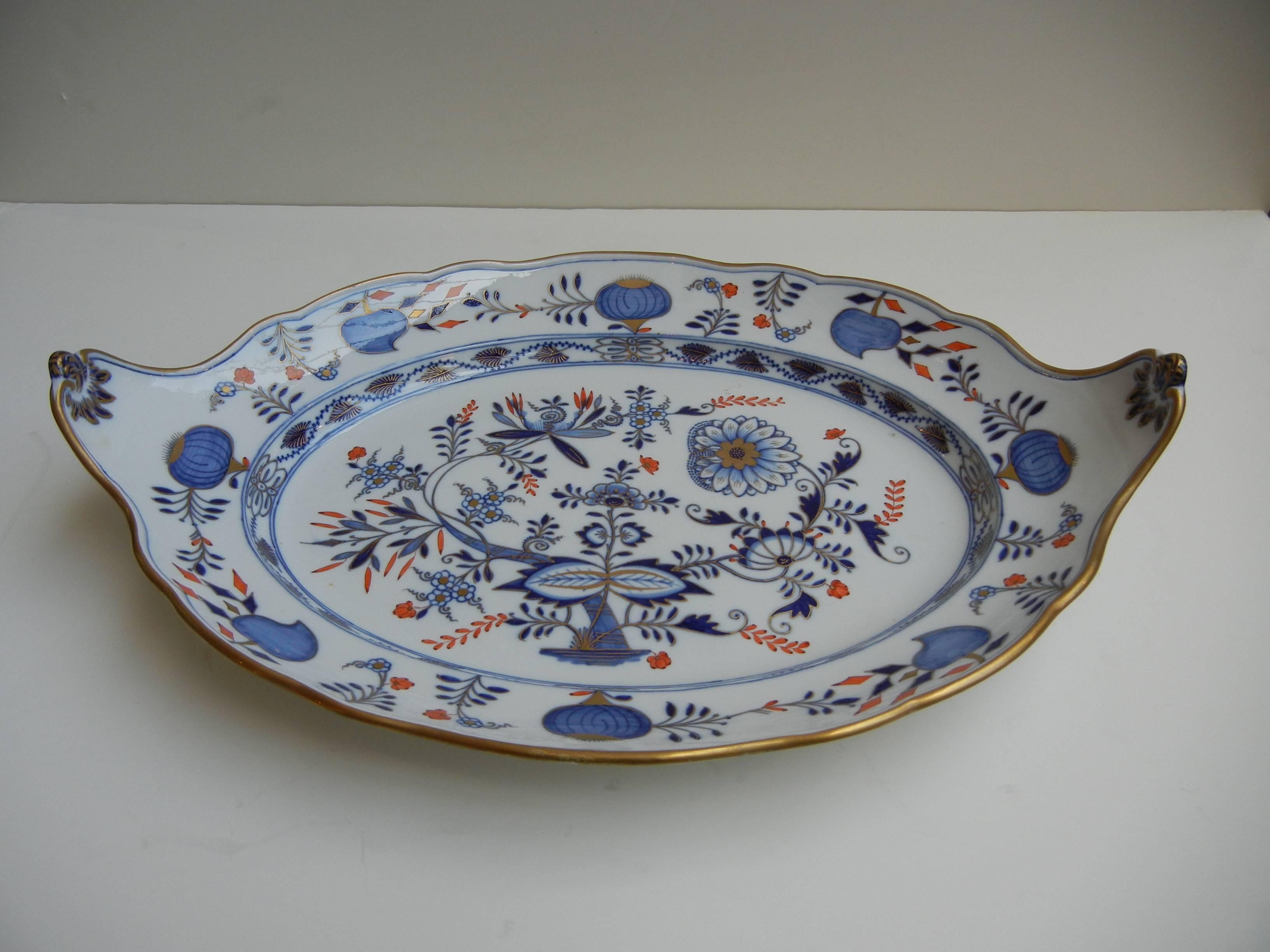 This beautiful Meissen platter is also hand decorated in gold and rust overtop the glaze of the blue onion pattern.

The shape is unusual with the two ends curved and raised as handles.

Early crossed swords mark on reverse.

Excellent