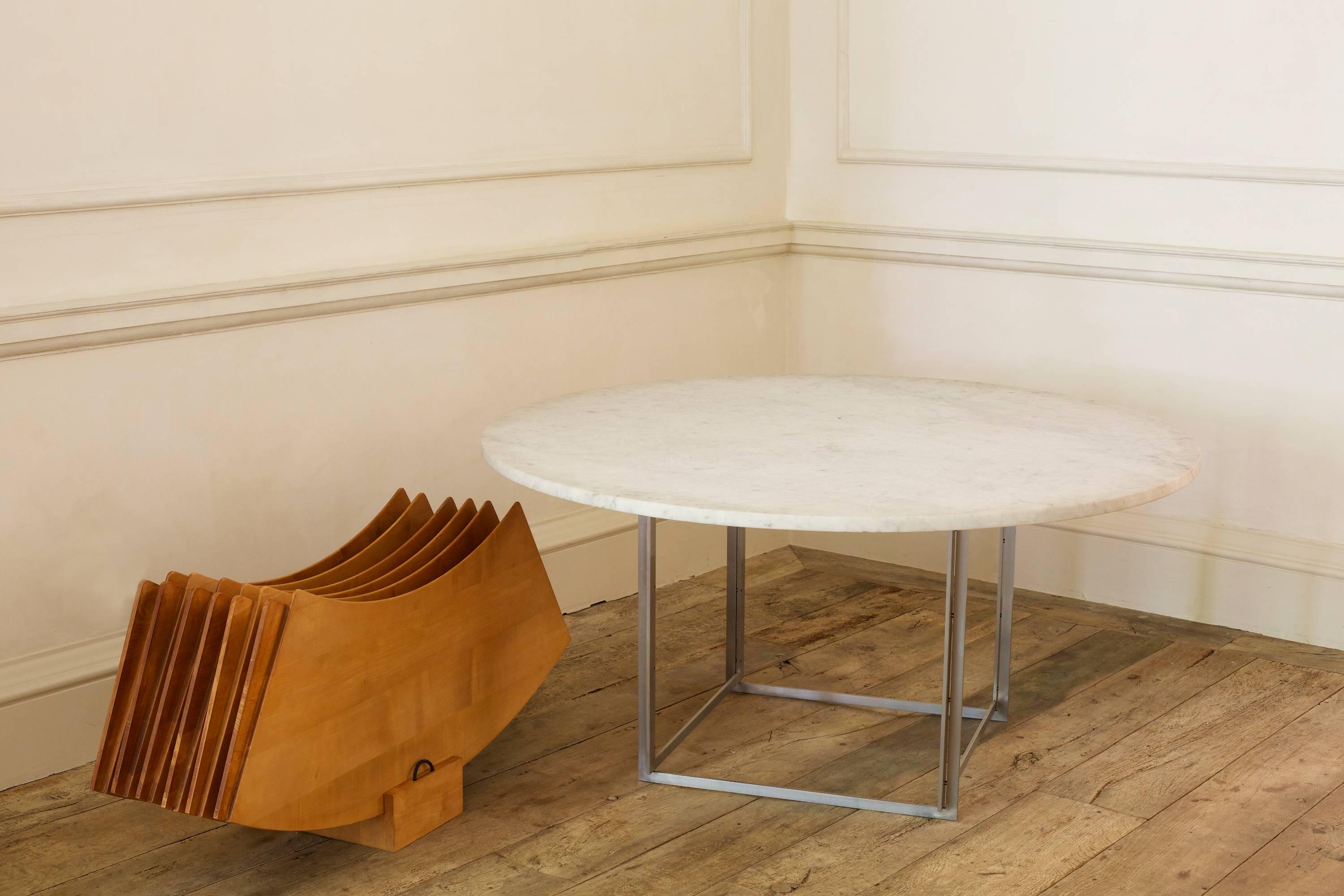 Designed by Poul Kjaerholm for E. Kold Chrstensen

White marble and matte nickel-plated steel with extra leaves in birch, with storage rack, that extends the diameter by 72cm

One of the defining features of the table is the birch extension