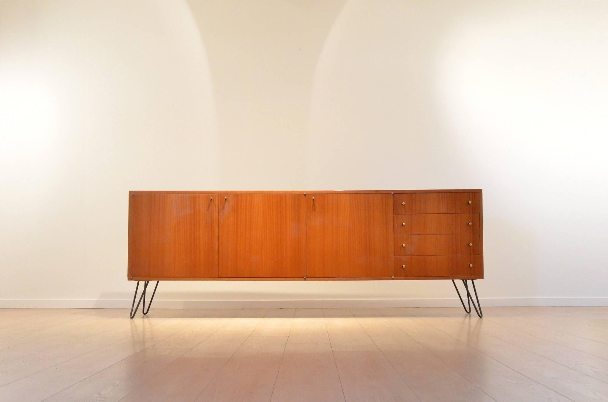 Large veneered mahogany sideboard with three sections composing four drawers and two x cupboard sections.
Beautiful V-shaped black wire metal legs.