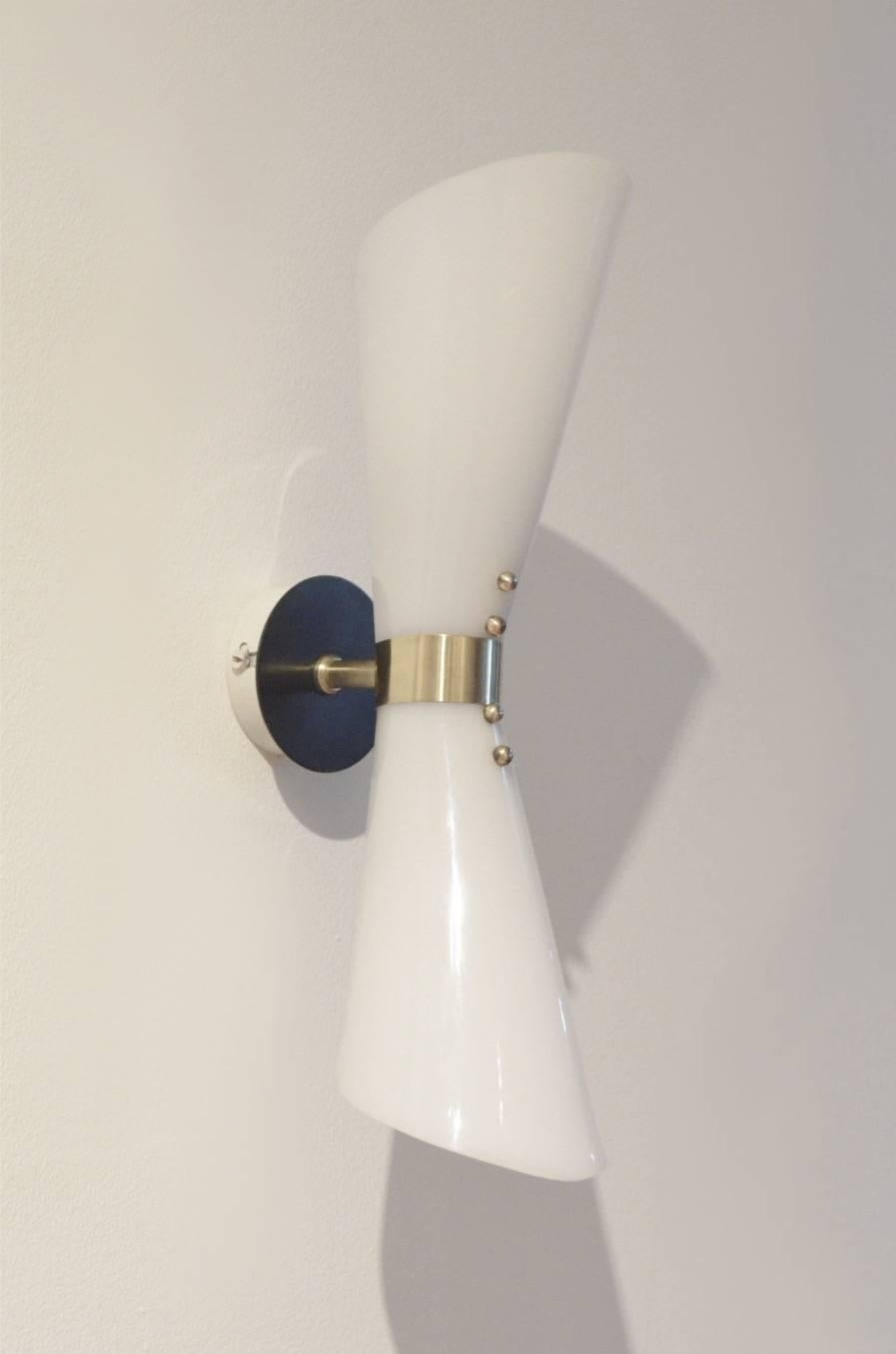 Decorative set of two Italian wall sconces made of a combination of black and white painted metal matched with brass and diabolo shaped plexiglass shades.