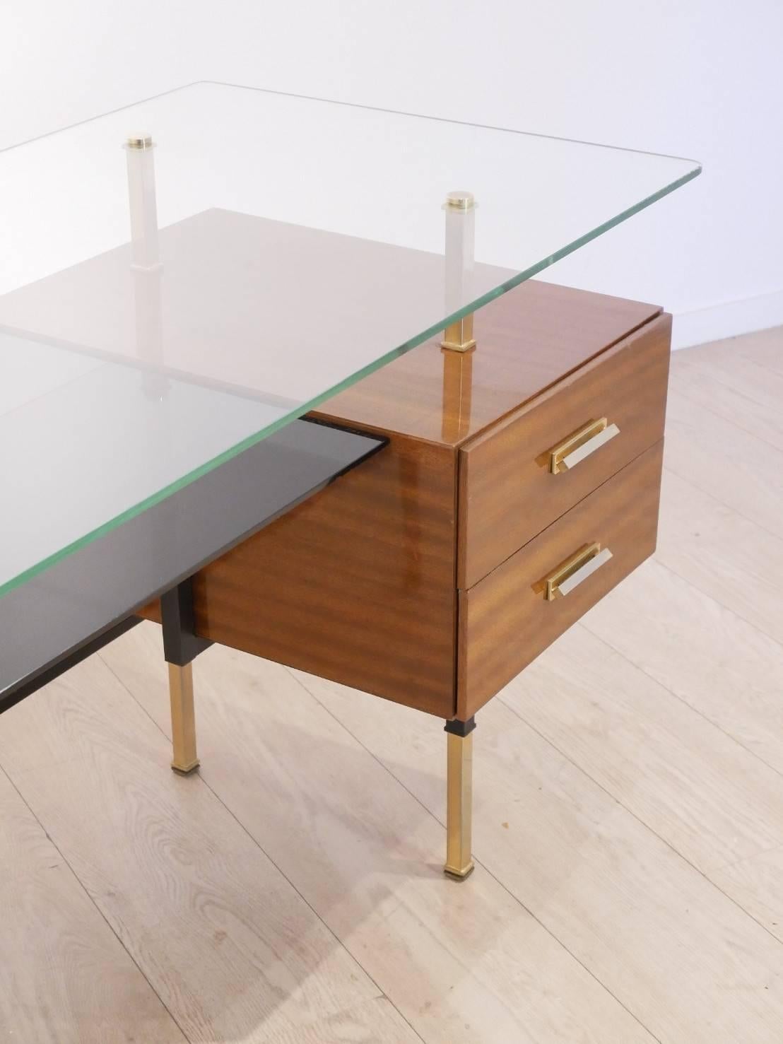 Rare modernist writing desk originating from France / mid 1950s, in the style of R.J Picard, Clear glass top matched with lower black opaline glass tray, shellac side unit in mahogany wood veneer and brass handles. The main structure is composed of