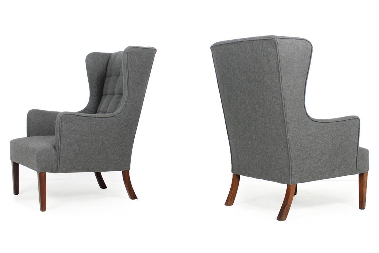 Very rare pair of Danish modern wingback lounge chairs from 1968 with tufted backs, grey wool, rosewood legs. Very high quality, beautiful and very rare. Completely restored, new upholstery and wool fabric. Never saw highback lounge chairs like