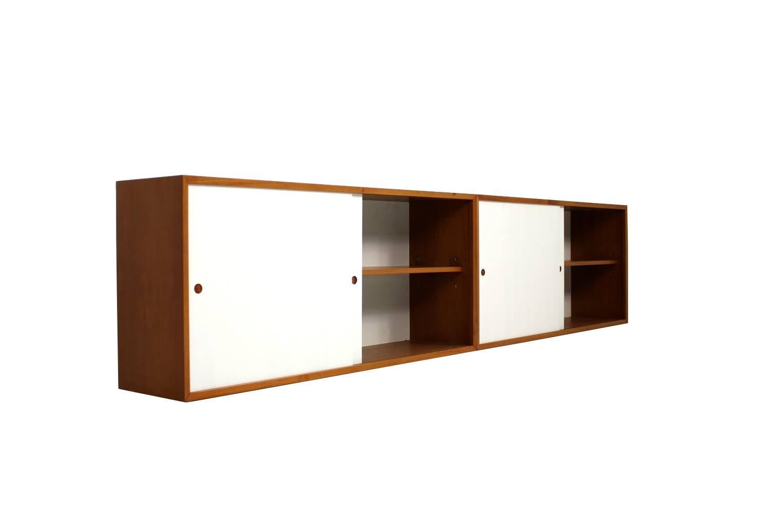 Beautiful wall-mounted, 1960s teak sideboard, attributed to Poul Nørreklit.
Danish modern design, white lacquered siding doors, very good condition.
Each element is ca. 127x56x30cm so together 254x56x30cm.
Variable shelf inside, fantastic Minimalist