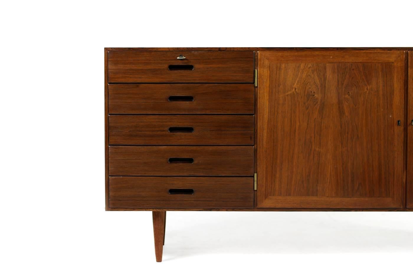 Beautiful Kai Winding sideboard, Denmark, 1960s made by PJ Poul Jeppesen, made in Denmark. Two doors and five drawers, fantastic condition, high quality, brass hinges, two keys available. Outside in rosewood, inside mahogany, solid drawers.