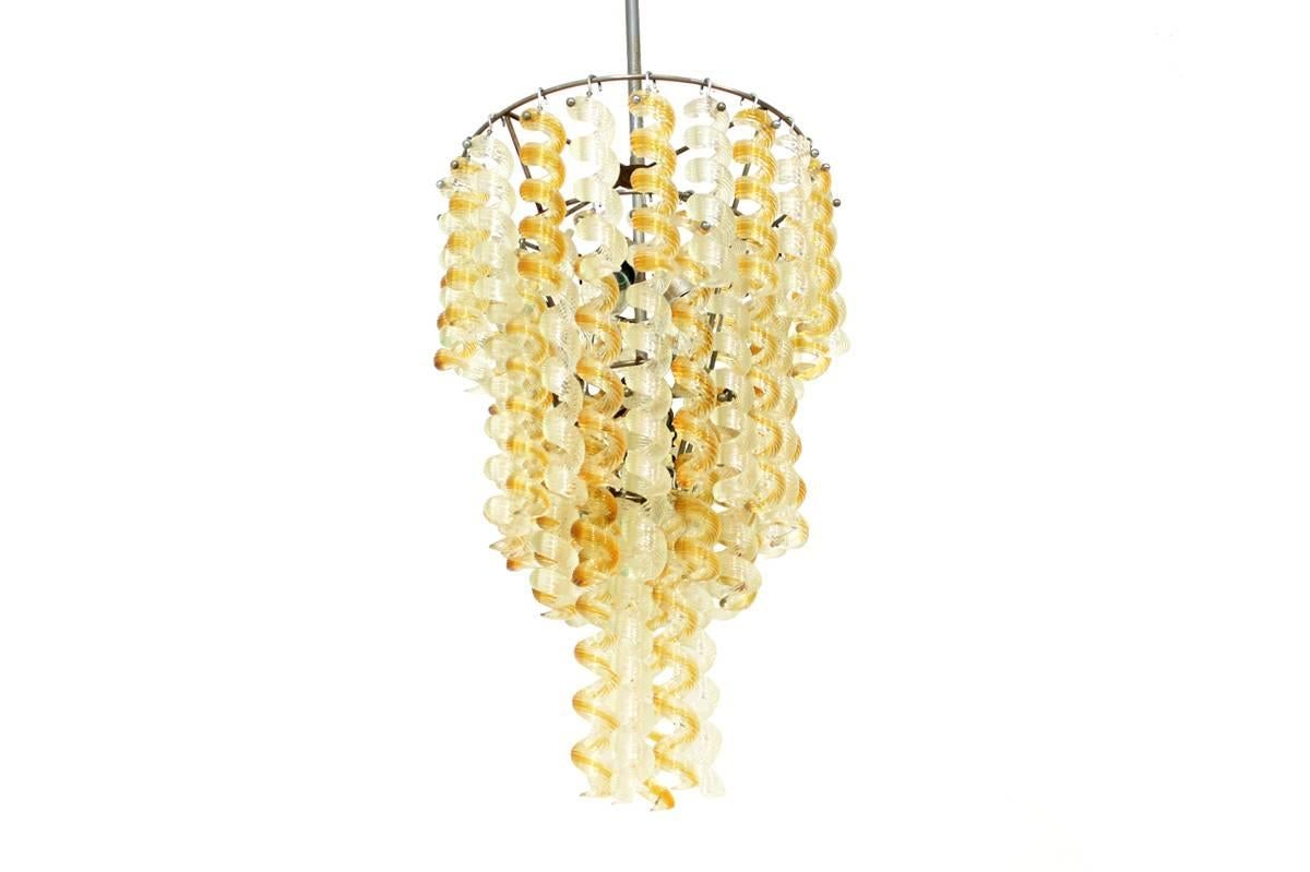 Beautiful and very rare italian mid century modern four-tier chandelier, with about 60 heavy weight full Murano glass parts, twisted glass, in amber and white. Frame with some patina, overall very good condition, no chips or cracks on the glass. For