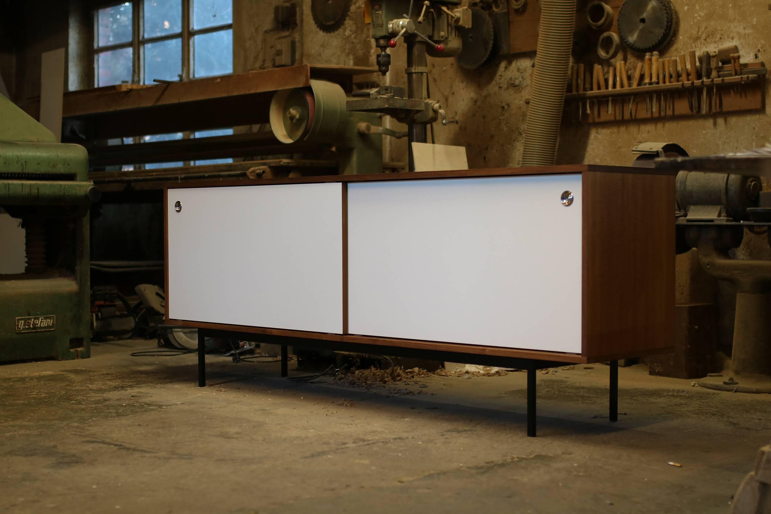 Beautiful teak sideboard, freestanding, Made in Germany, design by Nathan Lindberg (Nathan Lindberg Design)
White HPL (Formica) sliding doors with stainless steel door handles, iron base powder coated in black.
Best condition, the sideboard was