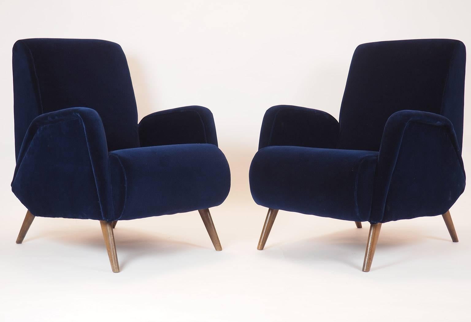 An enveloping deep 'blu notte'  -   Deep Blue color italian velvet ,  for this pair  of Italian luxurious  and charming armchairs. 
Geometrical shape characterize the fine design of the seat; the legs are in wood.
 New upholsterd and Covered with