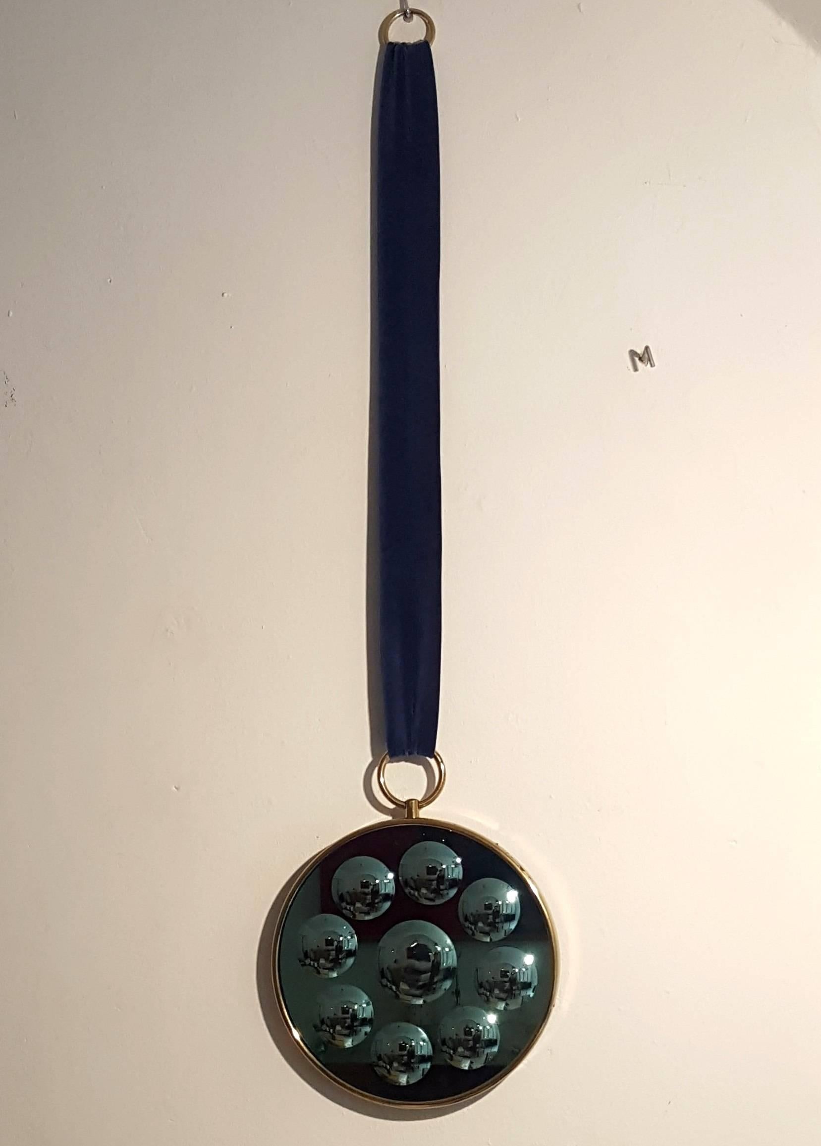 Very rare optical mirror by Piero Fornasetti with blue velvet band.
The mirror has a very fine light green color mirrored glass and
the brass frame has its original patina. Manufactured in Milano during 1960s.
Measures: Diameter 30 cm.
 