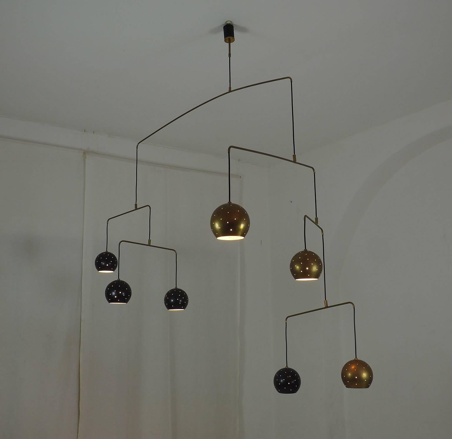 Original Italian brass mobile chandelier manufactured in a very small handcraft production in Milano. 20th Century
Large, magic and poetical mobile chandelier with brass and black suspending spheres; it can moves with the flow of air.
Wholly in