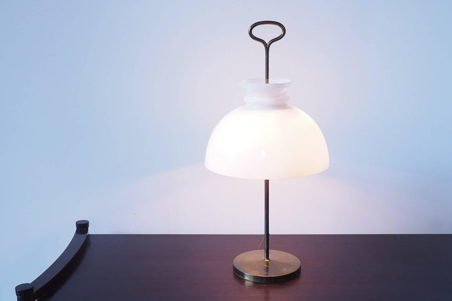 Designed by Ignazio Gardella for Azucena in 1956, the Arenzano table lamp in the early version with its original shade.
Original wire.
Brass structure and opaline glass reflector with 3 bulbs.
 