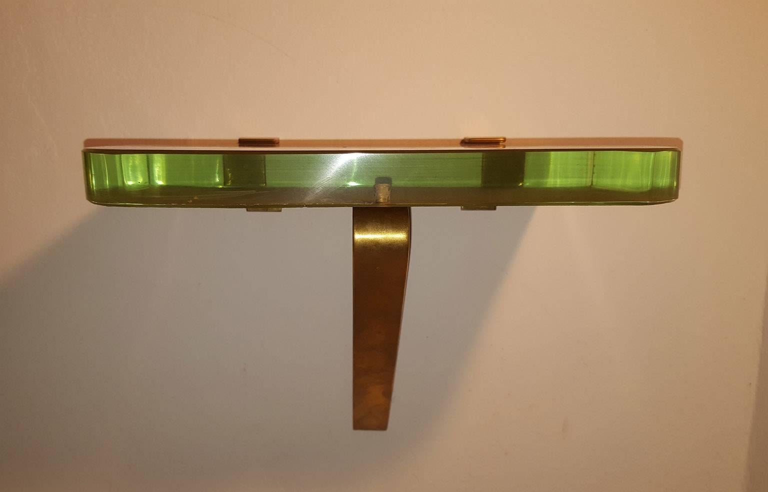 Extraordinary and unique couple of consoles with brass frame and thick glass Saint Gobain (33mm-1.3 inch) with gold background.
An elegant brass band supports the wonderful thick crystal nile green color.
The lower surface of the glass is golden