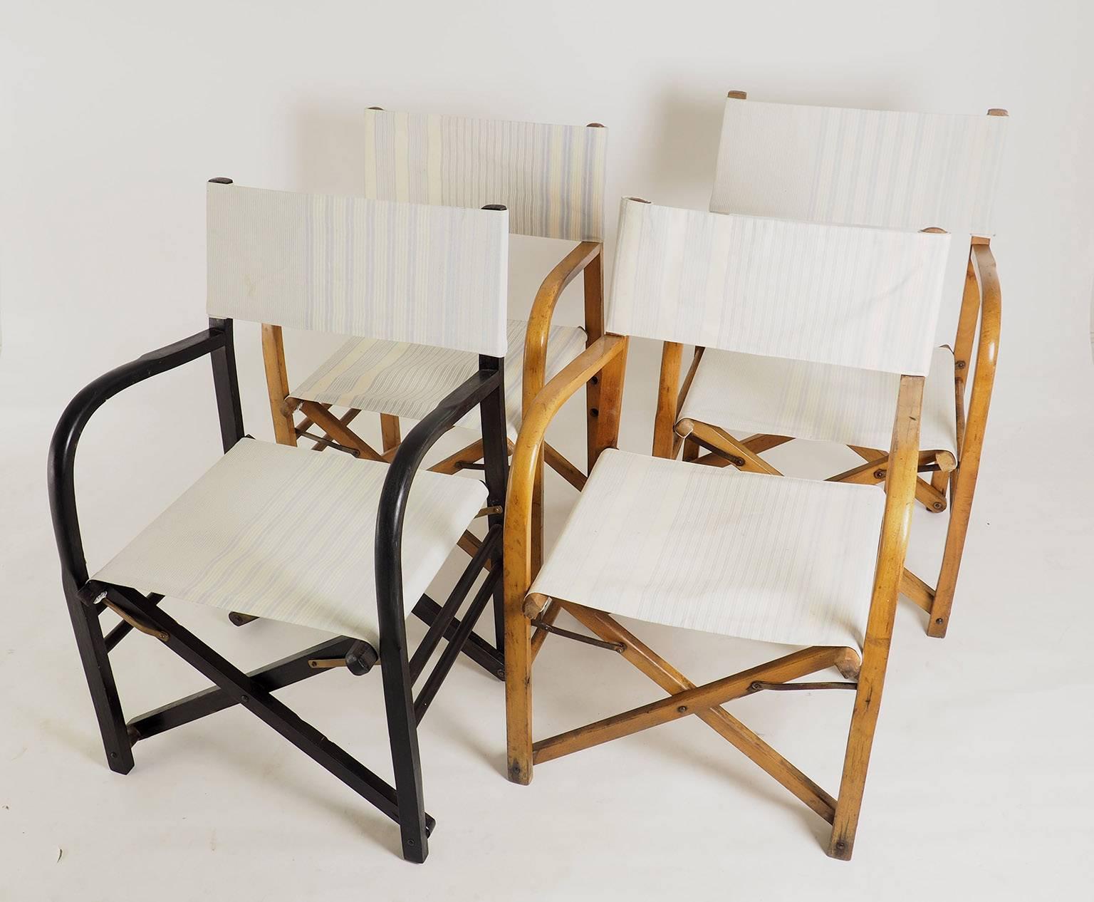 Set of four early folding Director's chairs from 1940s with strong cotton fabric. The set of four includes: three chairs in natural wood and one in black lacquered wood. Very original shape with large arms.