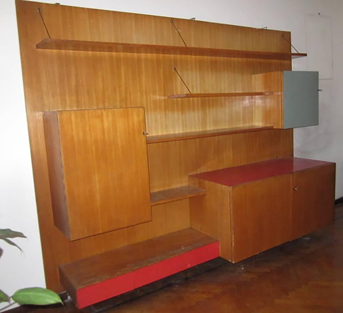 Italian large wall bookcase designed in Milano for a private commission in the middle of 1950s. By the architect Manzoni.
ashwood with colored Fomica inserts.
The shelves are supported by thin arms in brass.
 