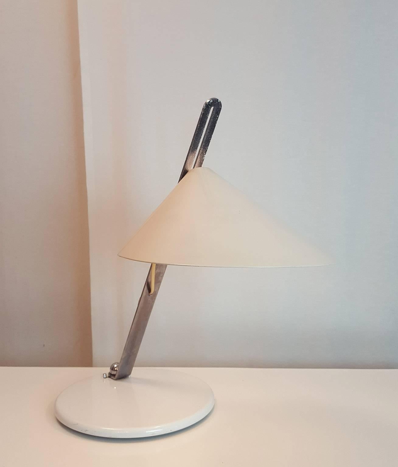 Nice table lamp completely adjustable;
pivoting plastic chromed arm on lacquered metal basement: white lacquered metal reflector that goes up and down on the arm.
Good original condition.