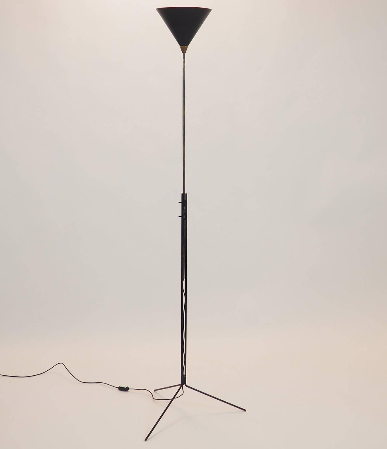 Rare and light adjustable floor lamp designed by Tito Agnoli during 1950s, with stem in natural brass sliding inside a tripartite structure in black brass.
Two brass cylinders allow fixing to the desired height of the Light cone.
The tripod basement