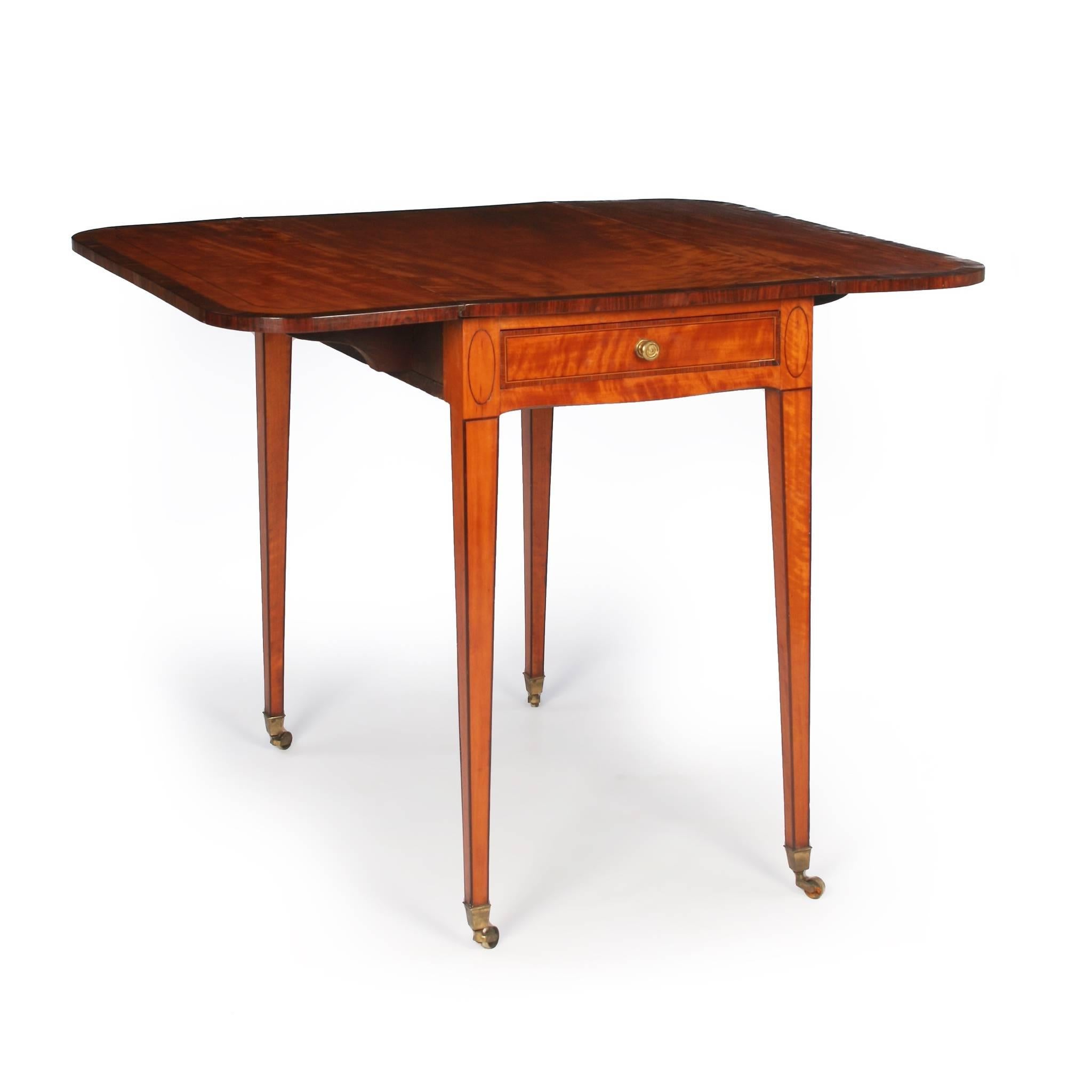 A fine quality Pembroke table contructed from nicely figured West Indian satinwood. The top cross banded in kingwood and with purplewood stringing, above a single drawer frieze and dummy opposing false drawer that are also strung in kingwood and