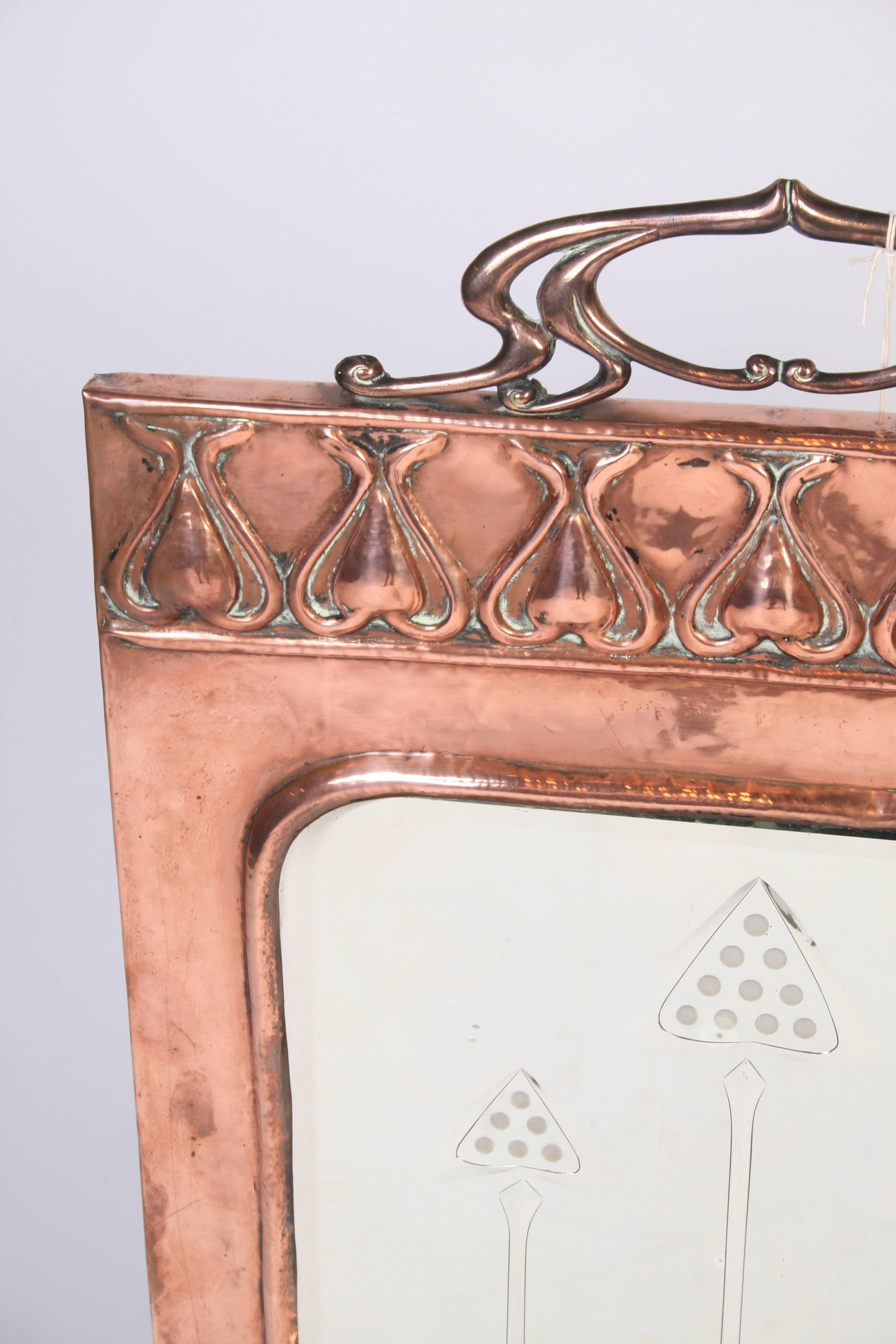 A stylish late 19th century copper fire screen having an etched inset mirror with styilized pattern above.