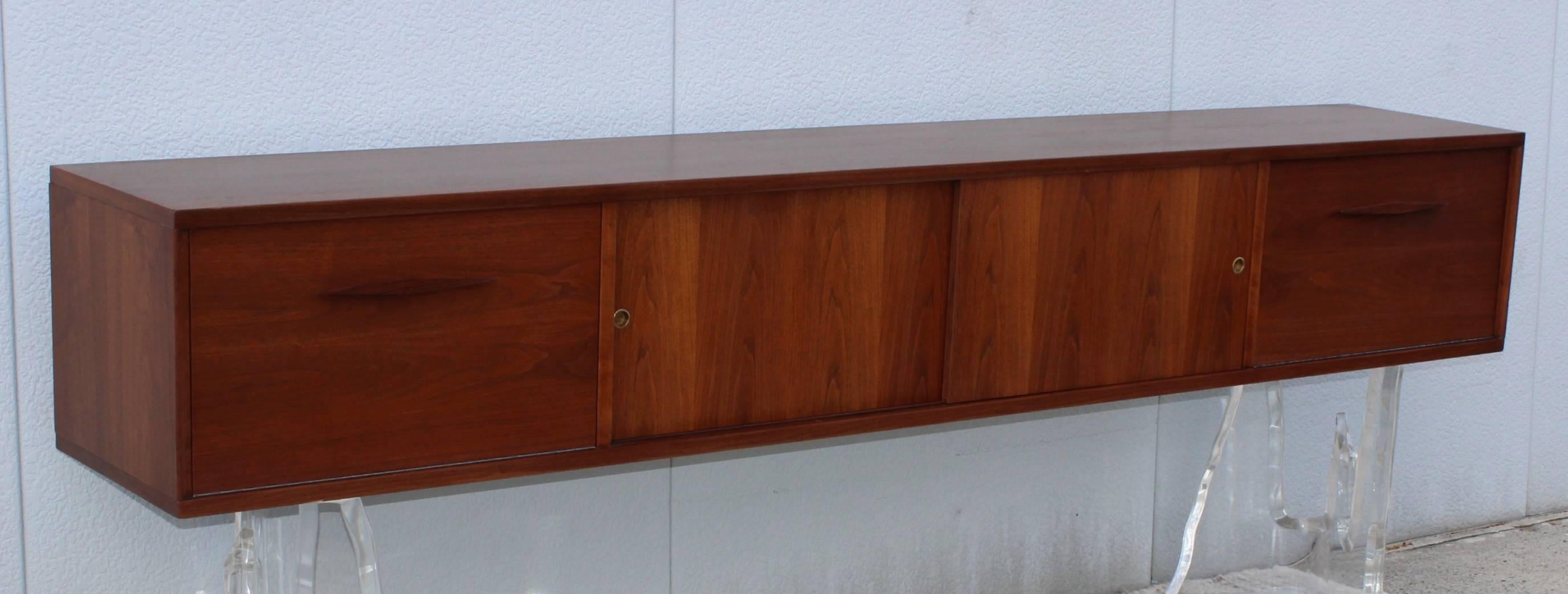 Stunning 1960s modern walnut wall-mounted cabinet or credenza.

Lucite bases are not included, they are for photography only.