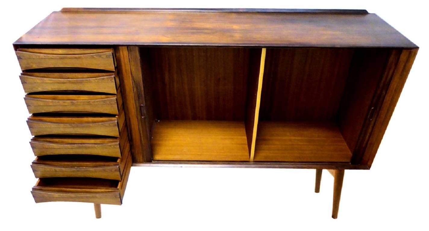 An exceptionally beautiful rosewood sideboard or buffet by Arne Vodder for Sibast Furniture. Seven drawers on the left and sliding tambour doors on the right concealing five adjustable shelves (not shown). Stunning.

The base is removable, if you