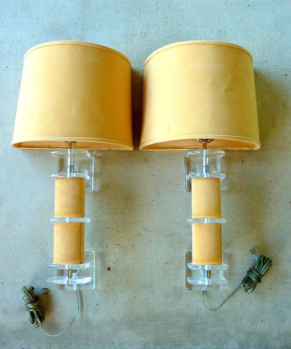 A rare pair of sparklingly clear Lucite sconces wrapped in faux suede, with matching faux suede demilune shades. Great design. Replace the faux suede to match your decor.

We have an extensive selection of vintage Lucite. If you are looking for a