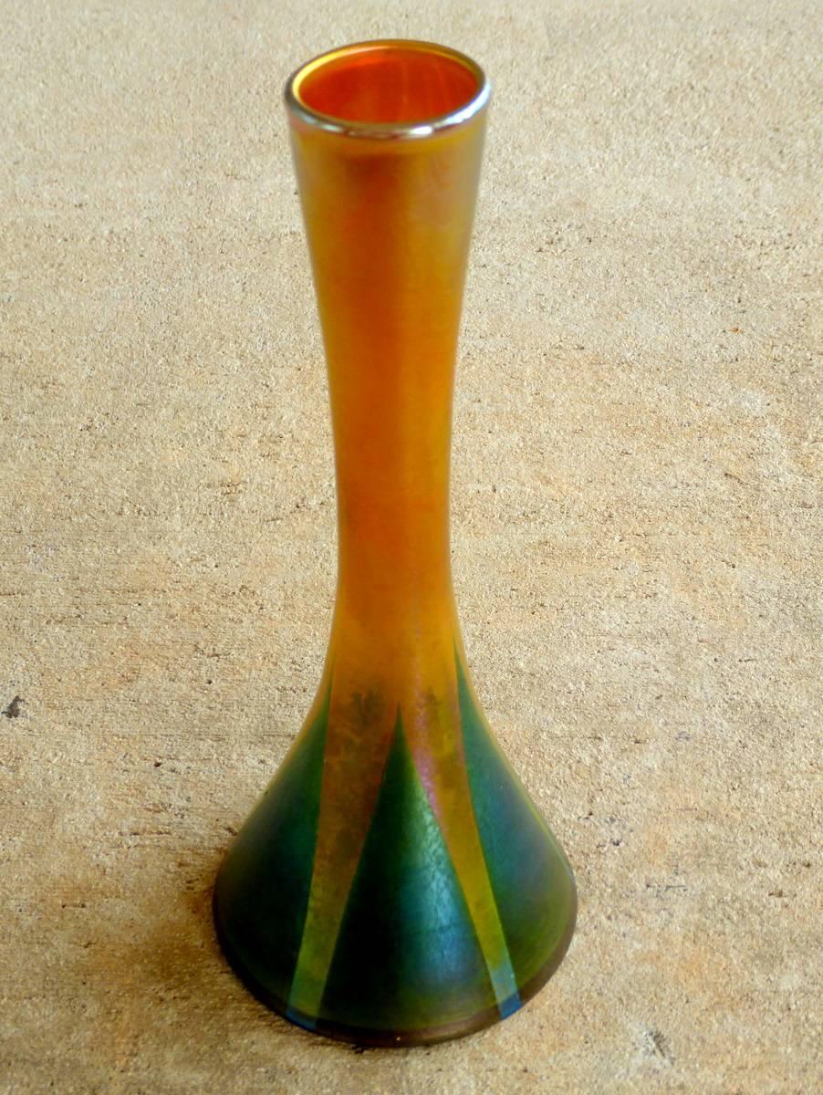 A lovely inverted trumpet form bud vase by Louis Comfort Tiffany, circa 1915. Favrile art glass in gold decorated with green and hints of blue. Signed L. C. Tiffany and numbered 1115-79852.

Favrile glass is a type of art glass known for its