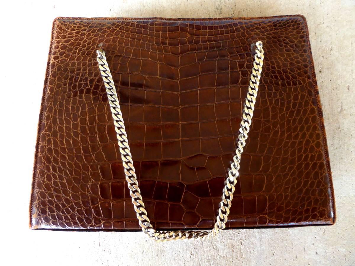 A stunning leather-lined brown alligator handbag by Lucille de Paris. Features four compartments: two slip, one zippered, and one with flap. Solid brass clasp.

A few general notes about all items available through 1stdibs dealer MOBLER  Home