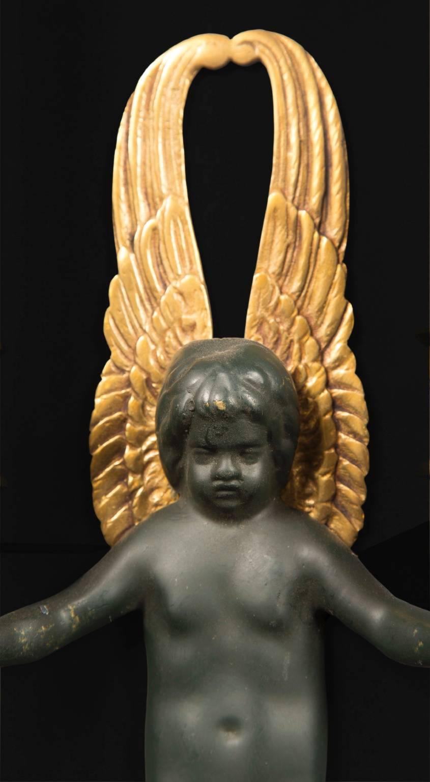 Este hermoso par de apliques de estilo Imperio son de fabricación italiana en bronce. Un niño alado, conocido como putti, está centrado en cada una de ellas en bronce verde oscuro, con las alas en dorado. Cada niño sostiene un par de velas, una en