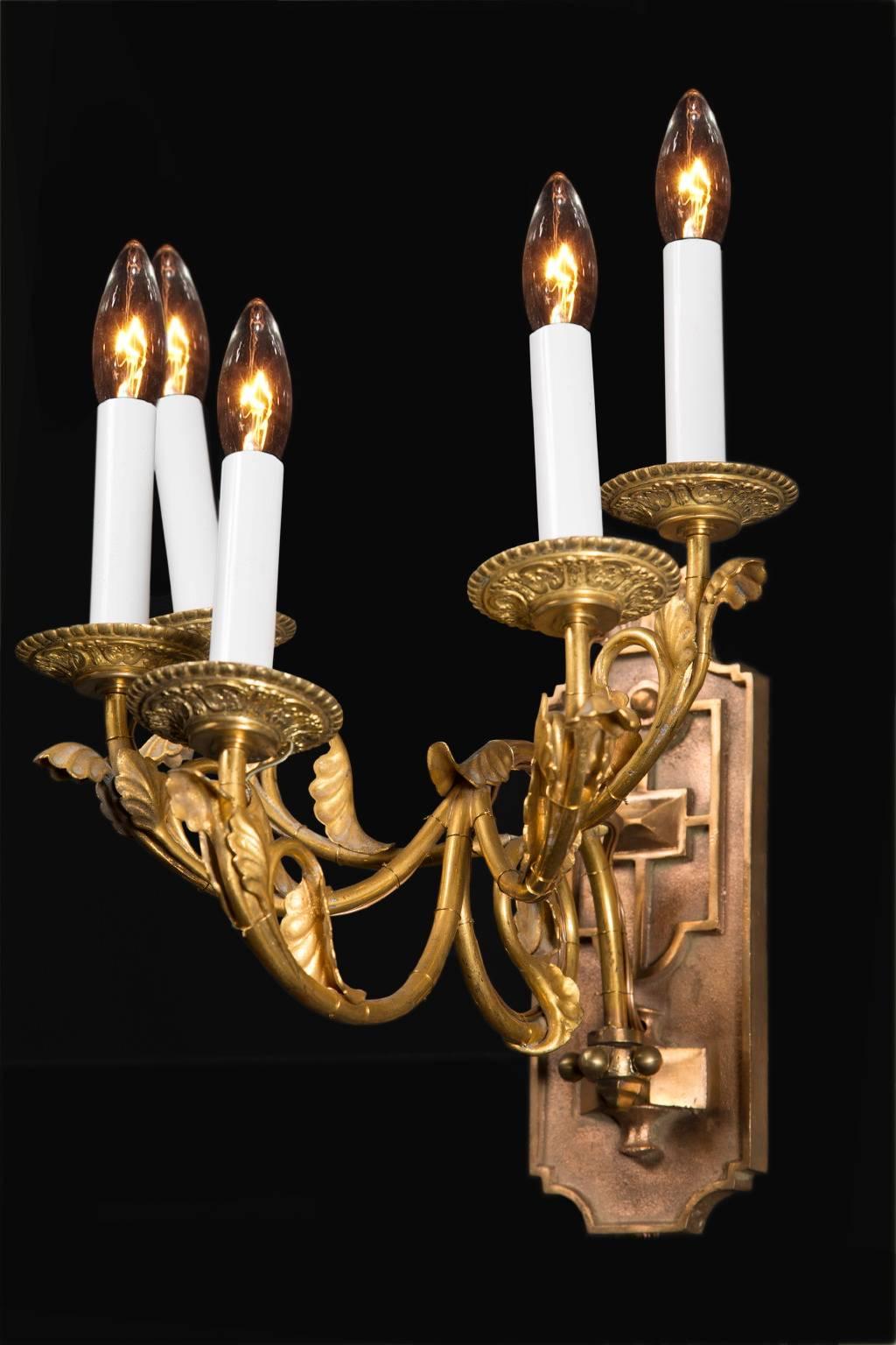 An unusual pair of French sconces, these were made in the early 20th century. Made of bronze, they are Louis XVI style, with five light on each sconce. A heavy backplate is decorated with a geometric pattern and elaborate bronze bobeches sit on the
