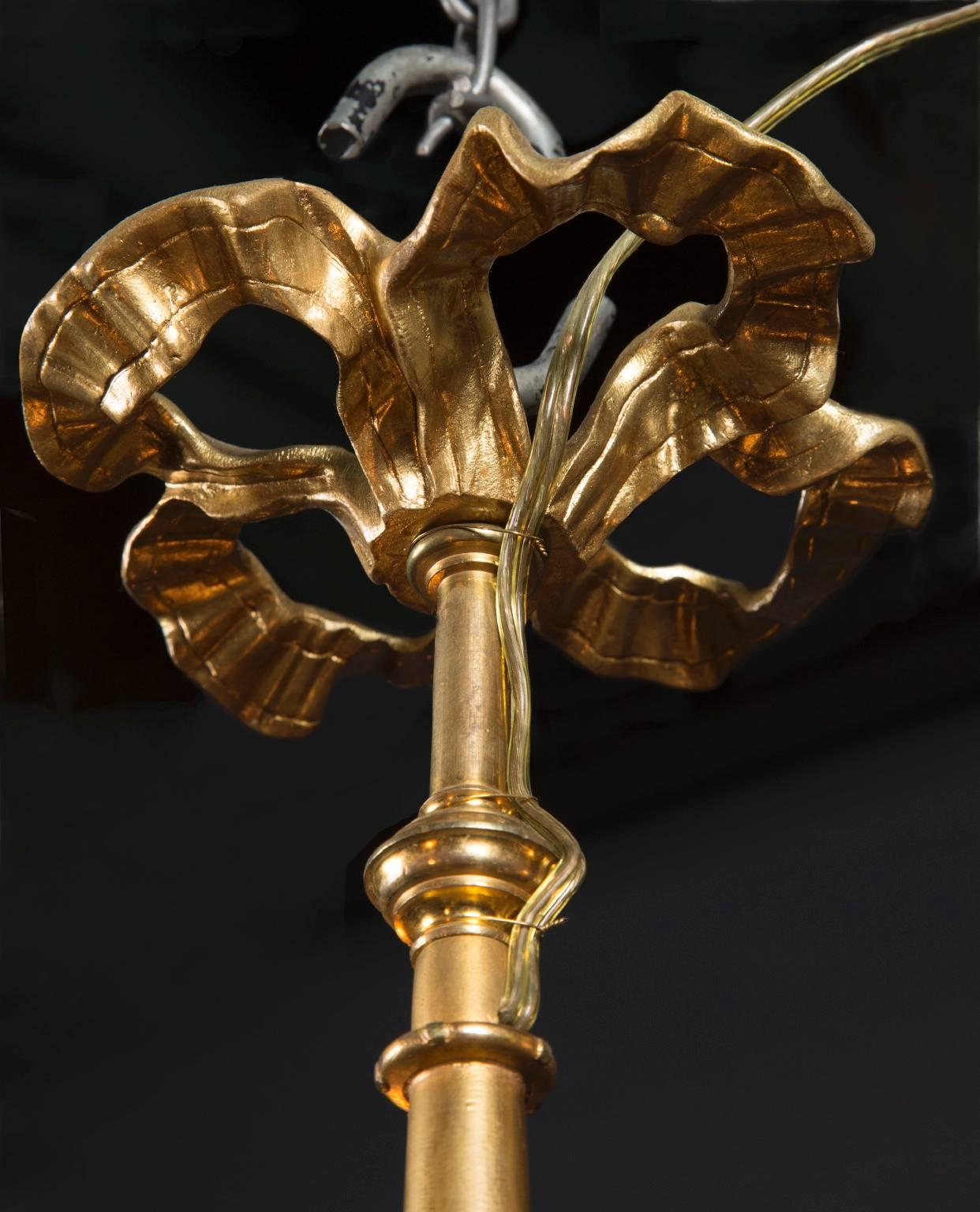 Ce lustre français de style Louis XVI en bronze d'orge, datant du XIXe siècle, est d'une élégante simplicité. La pièce présente un ruban métallique coulant au sommet, avec trois lumières disposées sur trois bras en dessous qui sont ornés de bobèches