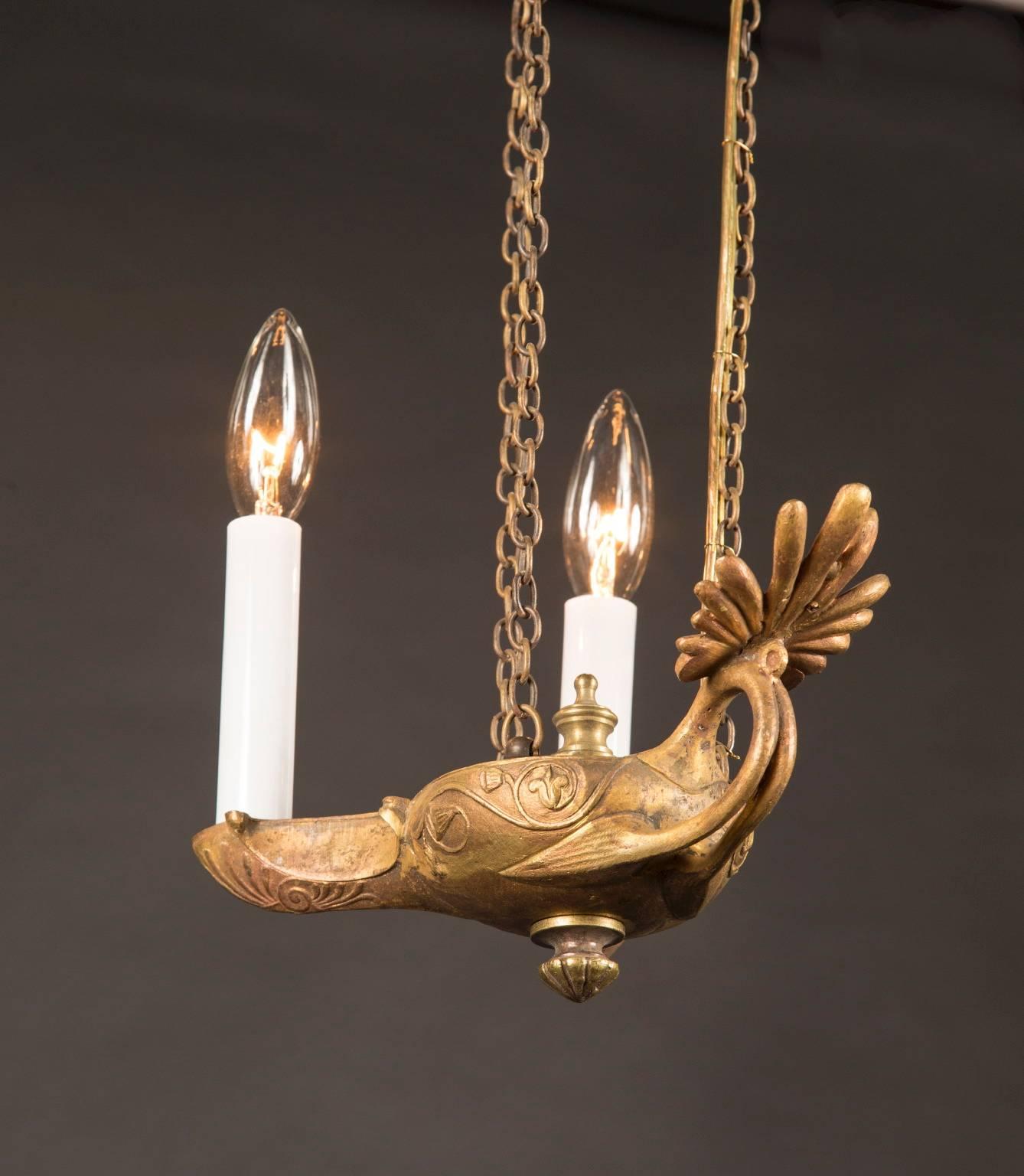 This pair of French bronze hanging oil lamps dates back to the 19th century and suspend from beautifully elaborate heavy chain. The crown resembles a gothic revival sunburst, connecting to the lamp in three positions. The lamp itself features