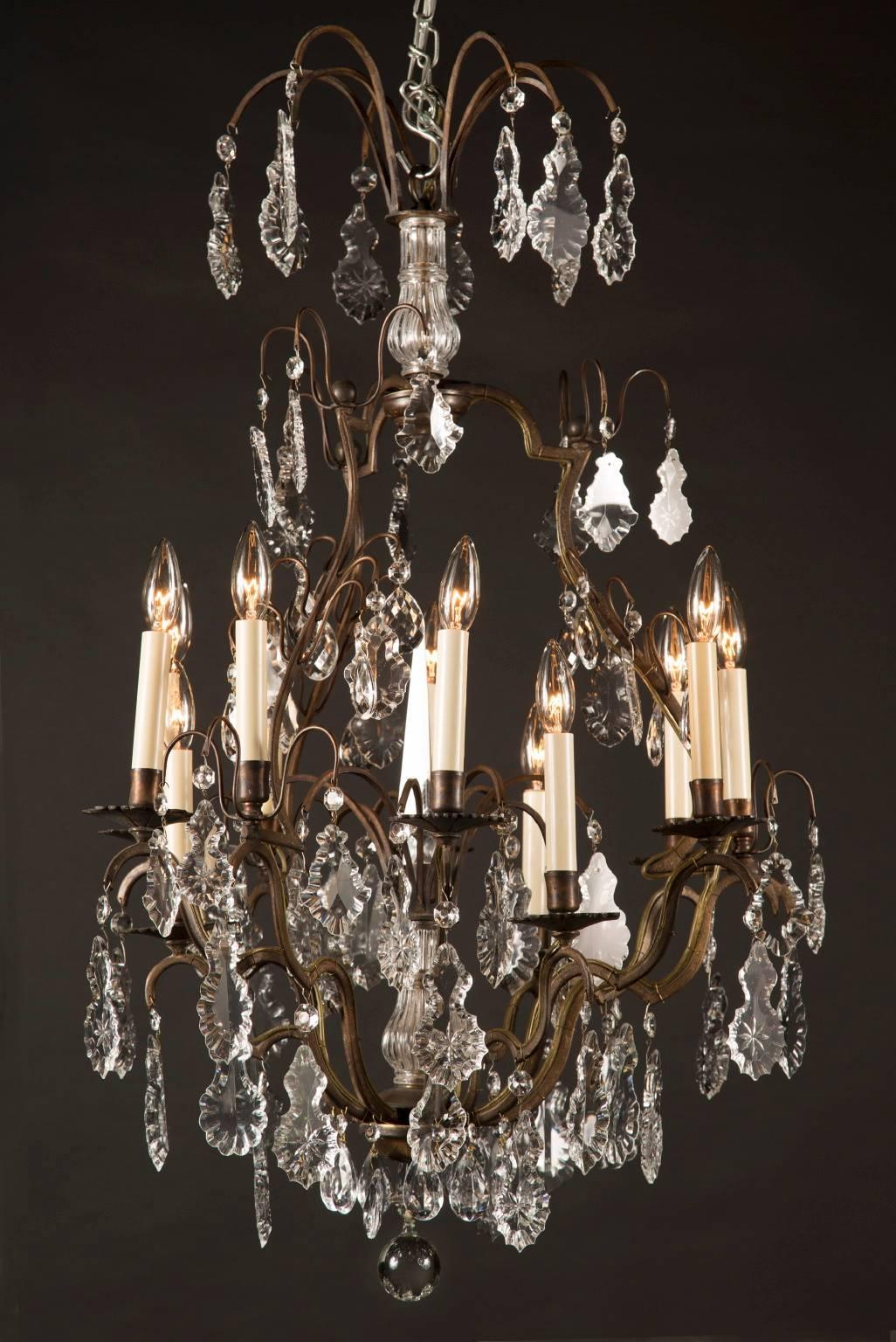 This chandelier is made with a dark bronze frame, which has then been draped with beautiful crystal plaquettes. A crystal ball hangs from the finial. The chandelier is topped with a crown of curved bronze arms supporting crystal plaquettes, all of
