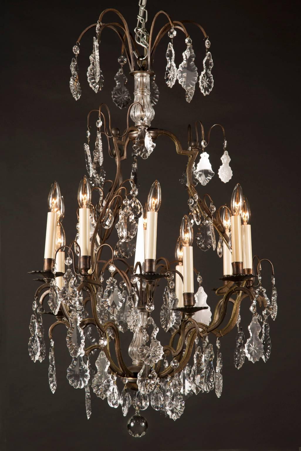 Questo lampadario è realizzato con una struttura in bronzo scuro, che è stata poi drappeggiata con bellissime placche di cristallo. Una sfera di cristallo pende dal terminale. Il lampadario è sormontato da una corona di bracci in bronzo ricurvi che